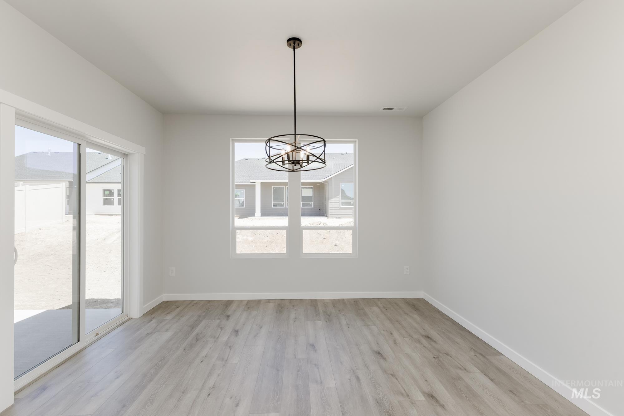 Unfurnished room featuring a chandelier and light wood-style flooring