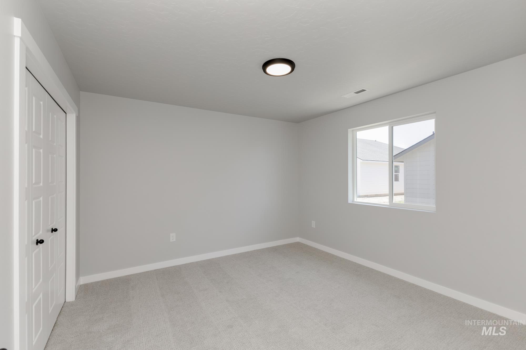 Unfurnished bedroom with light carpet and a closet