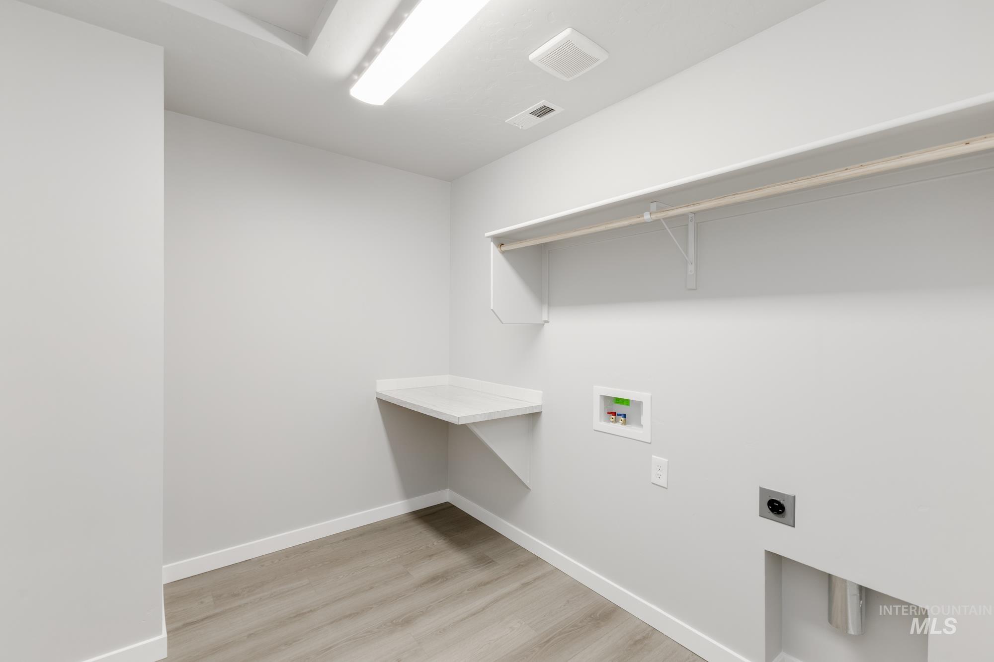 Laundry area featuring hookup for an electric dryer, light wood-style flooring, and washer hookup