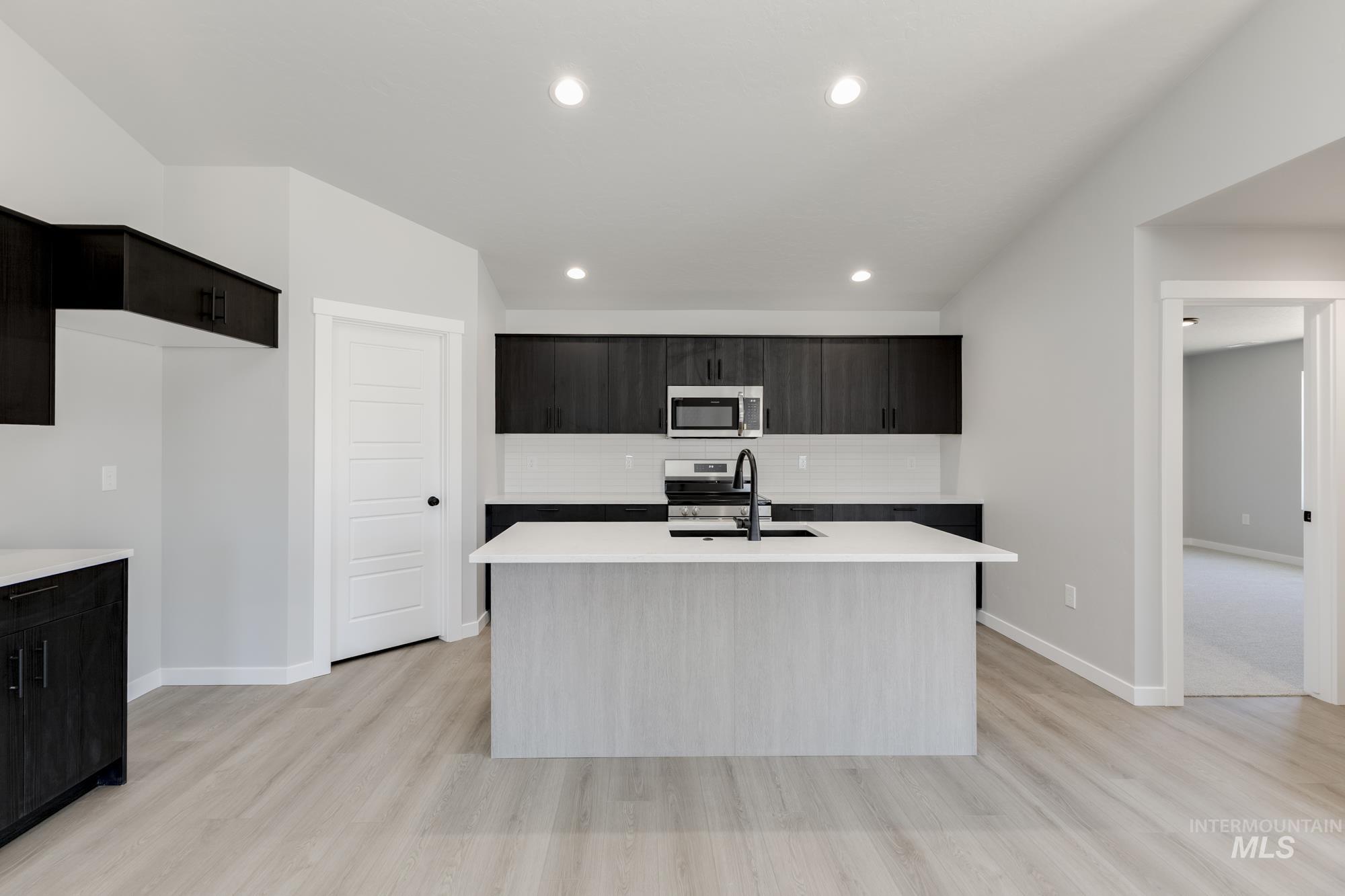 Kitchen with stainless steel appliances, light countertops, tasteful backsplash, light wood-style flooring, and recessed lighting