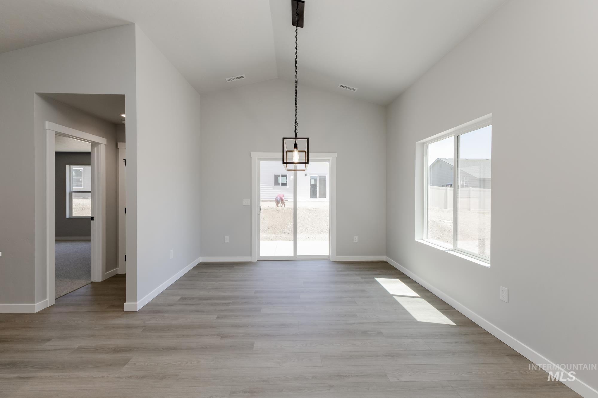Unfurnished dining area featuring lofted ceiling and light wood-style flooring