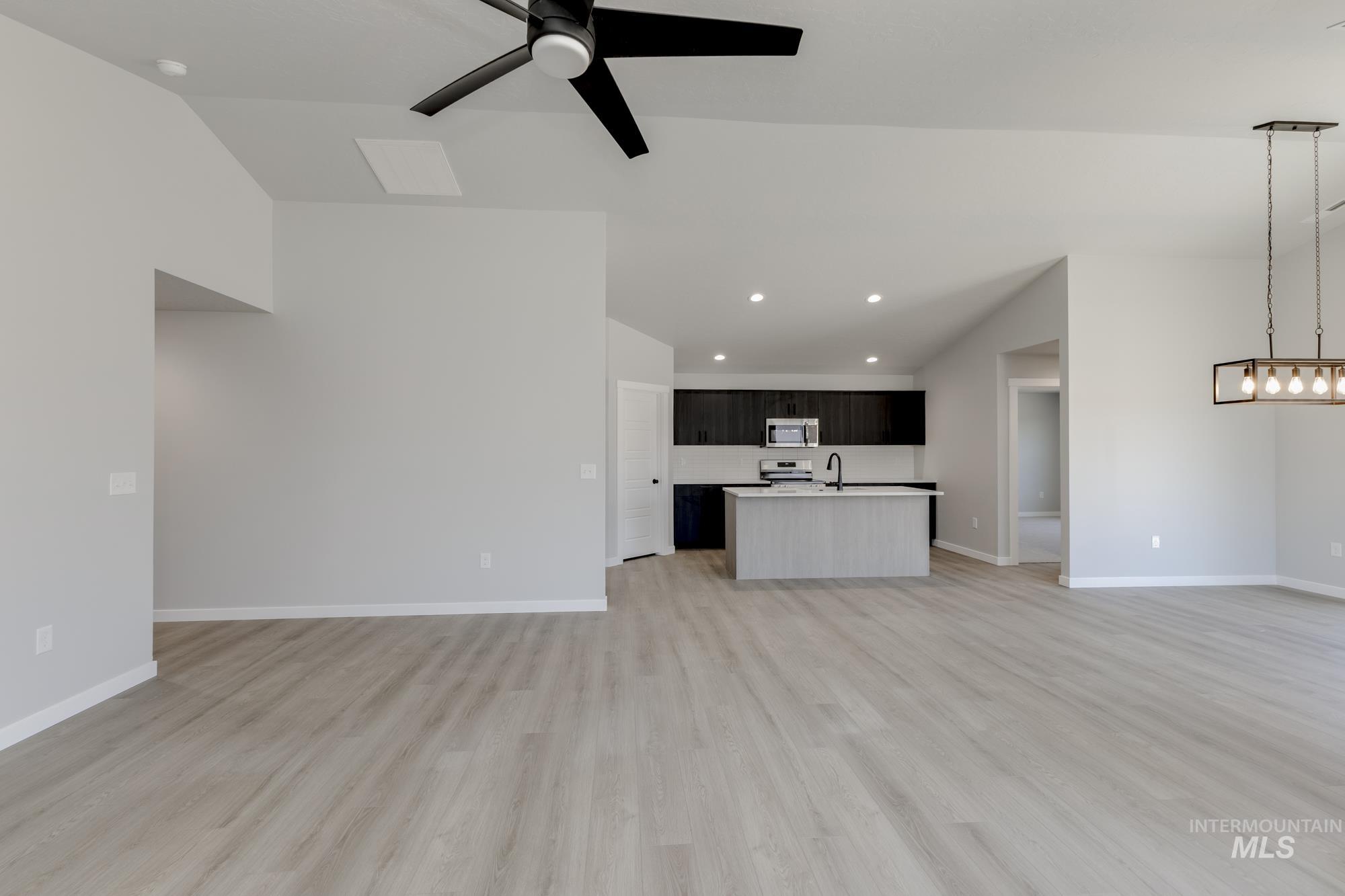 Unfurnished living room featuring lofted ceiling, light wood-style flooring, ceiling fan, and recessed lighting