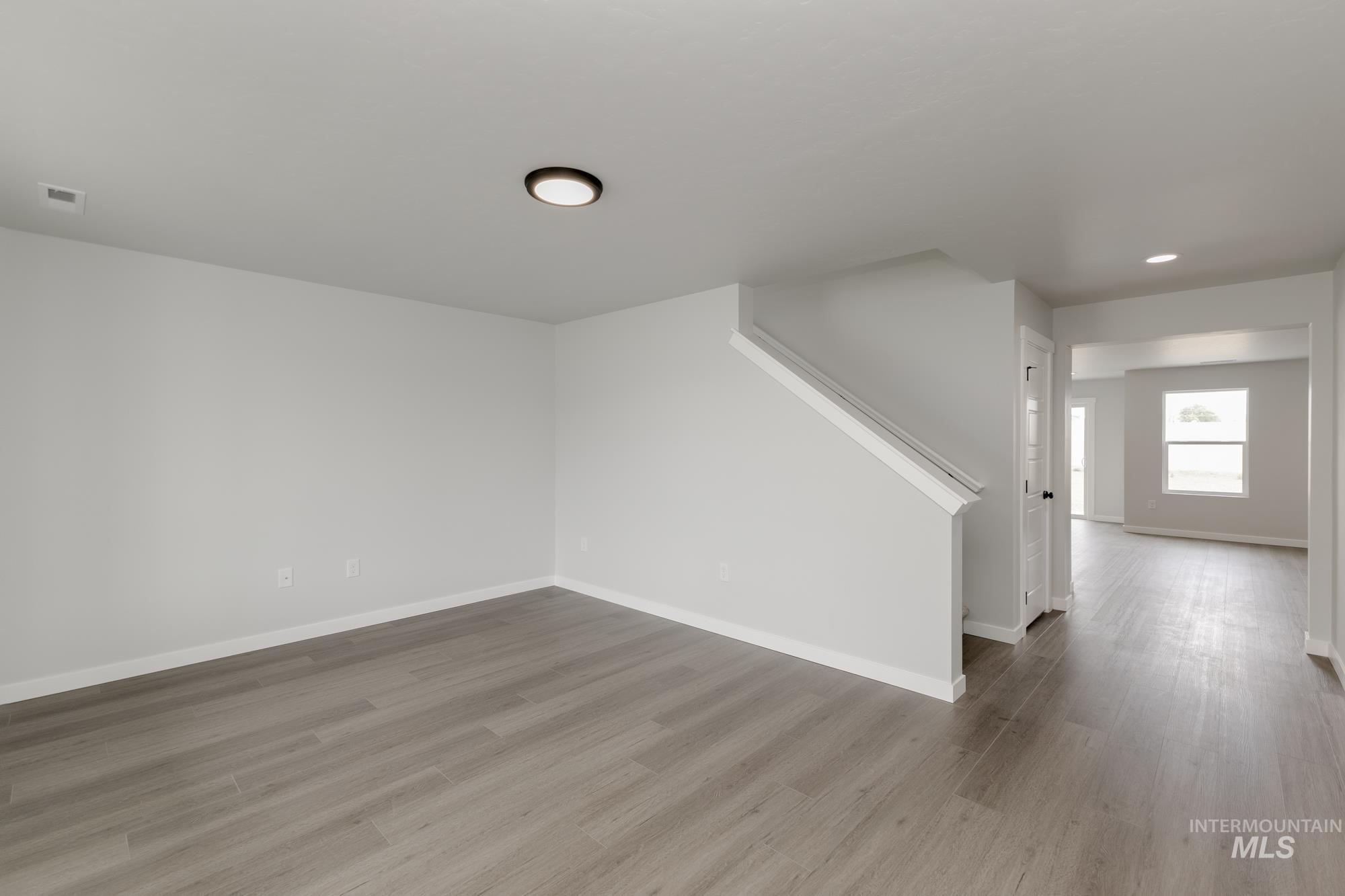 Unfurnished living room with wood finished floors and stairs