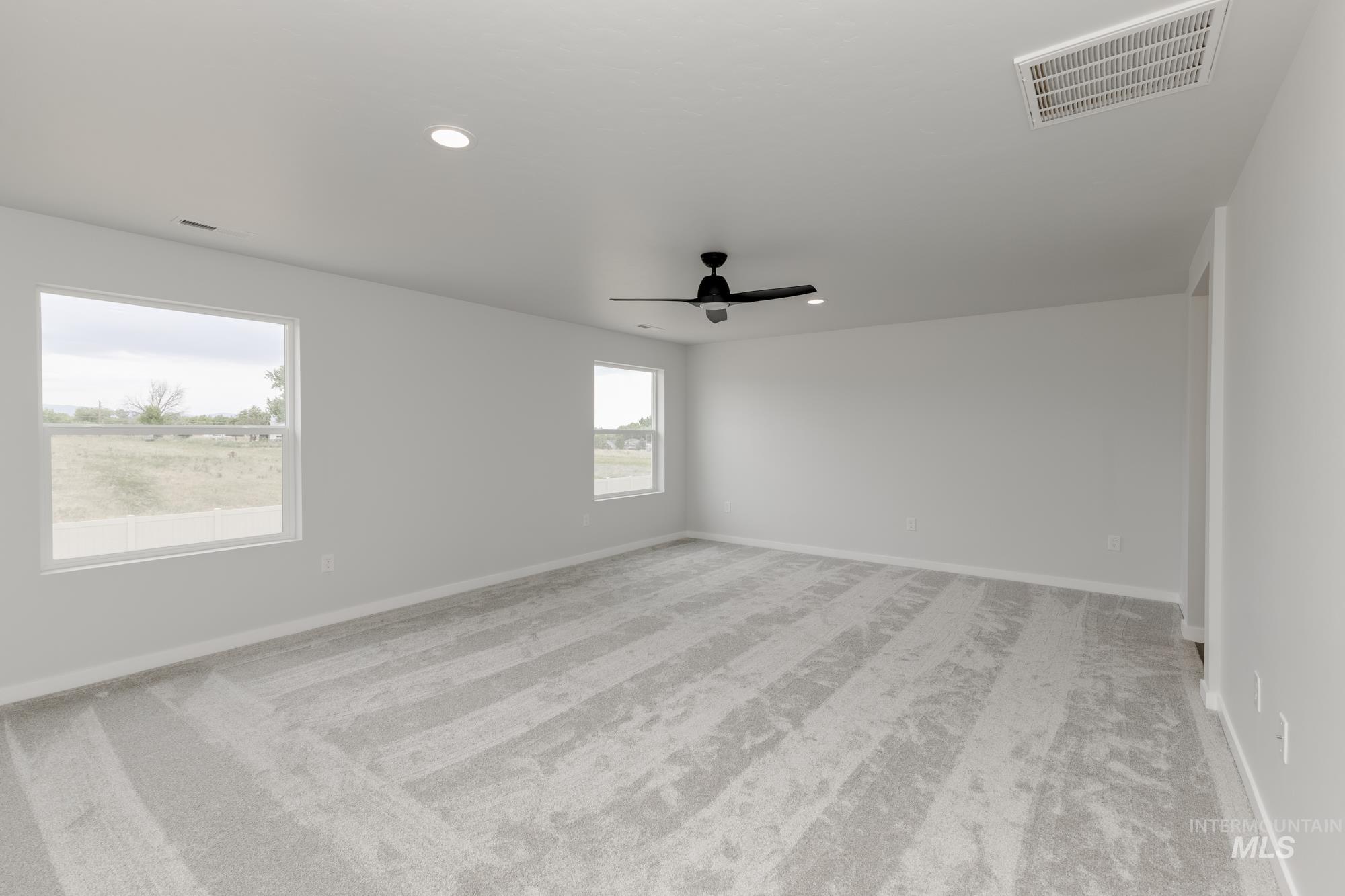 Spare room featuring light colored carpet, a ceiling fan, and recessed lighting
