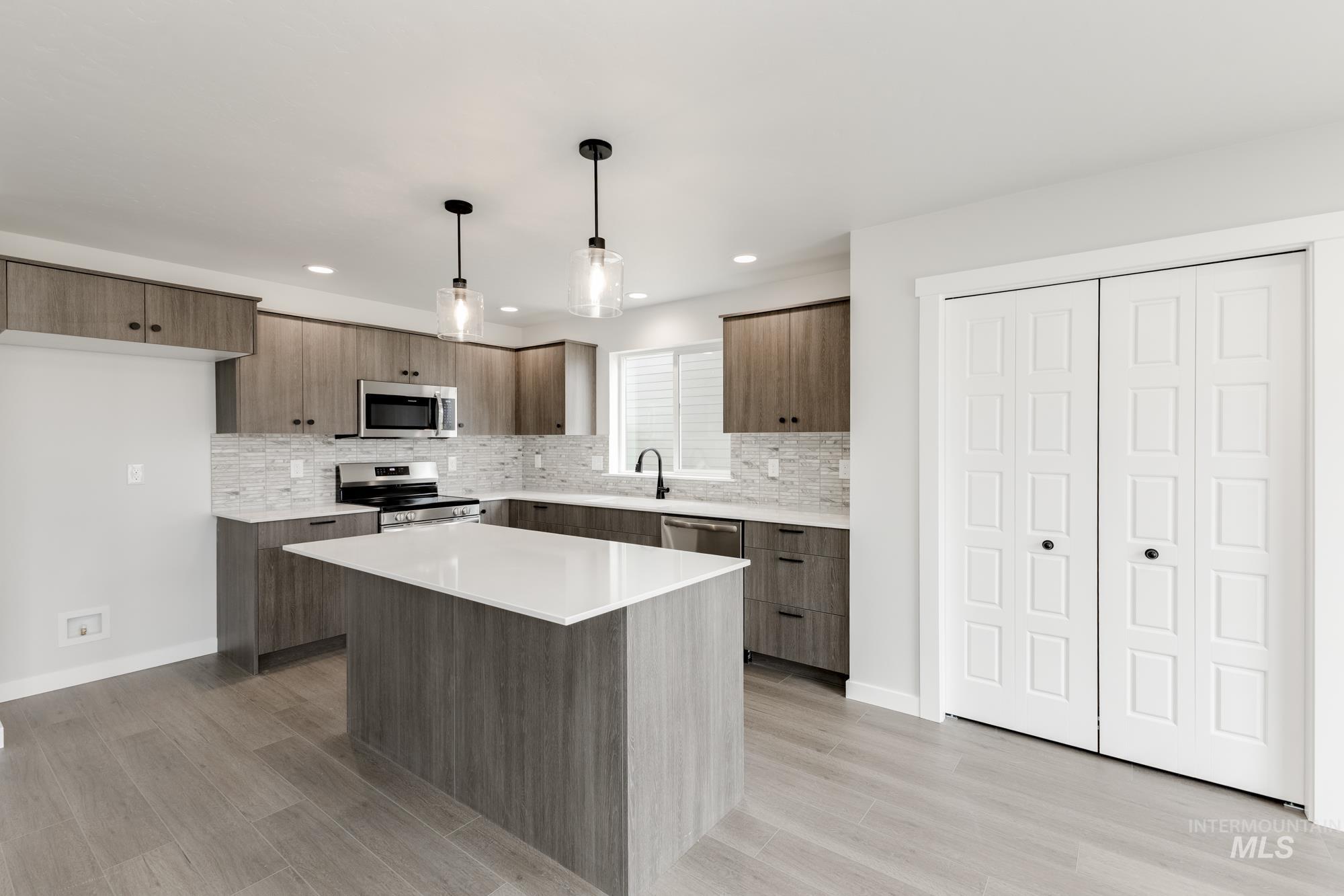 Kitchen with appliances with stainless steel finishes, modern cabinets, tasteful backsplash, light wood finished floors, and recessed lighting