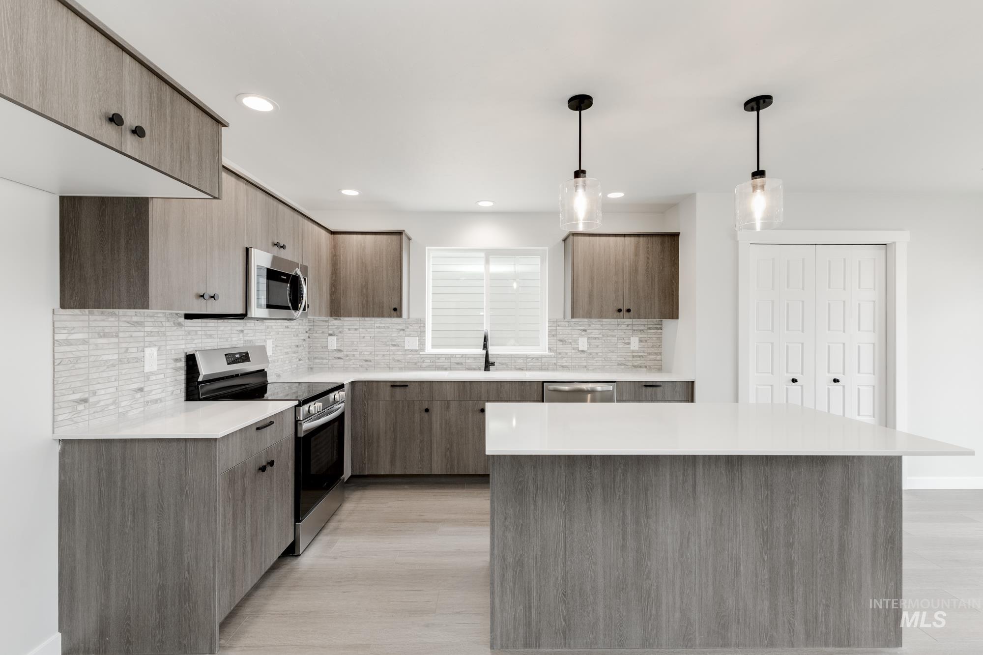 Kitchen with stainless steel appliances, light countertops, backsplash, modern cabinets, and recessed lighting