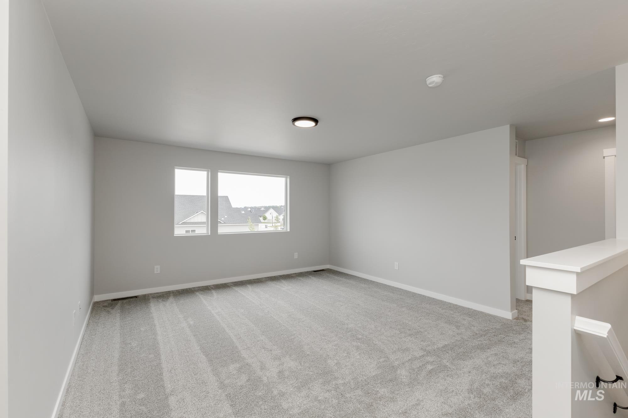 Empty room featuring carpet floors and a smoke detector