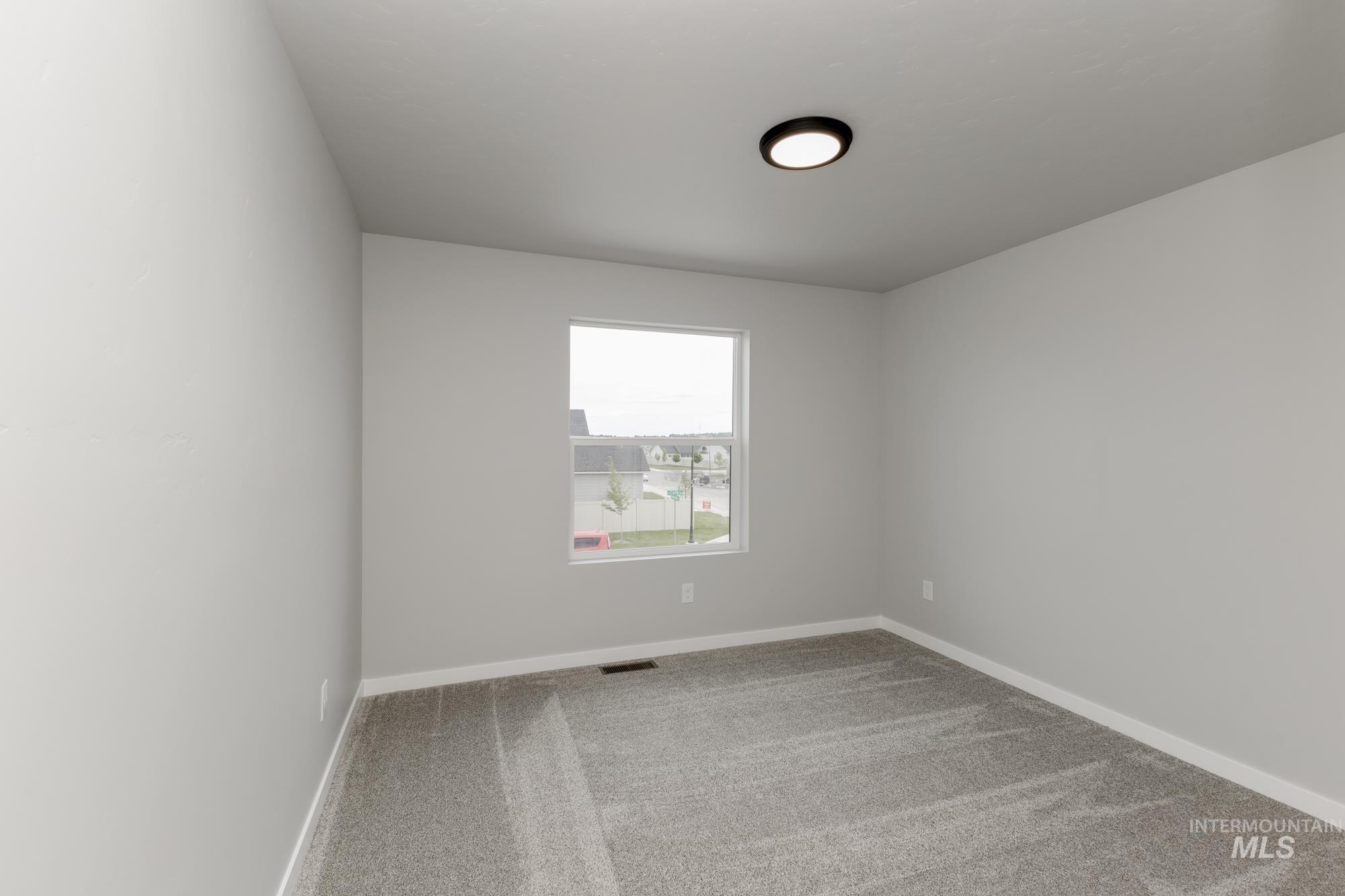 Carpeted spare room featuring baseboards