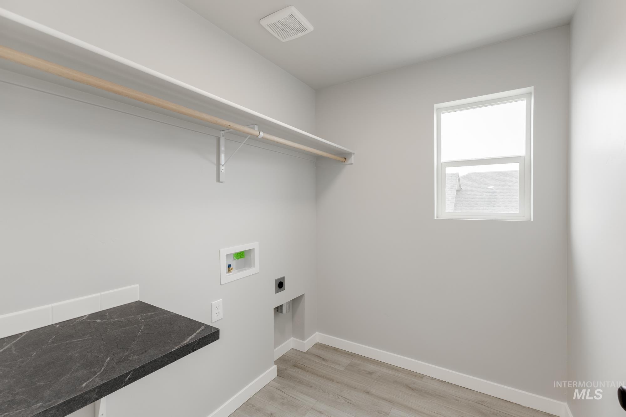 Laundry area with hookup for a washing machine, hookup for an electric dryer, and light wood-style flooring