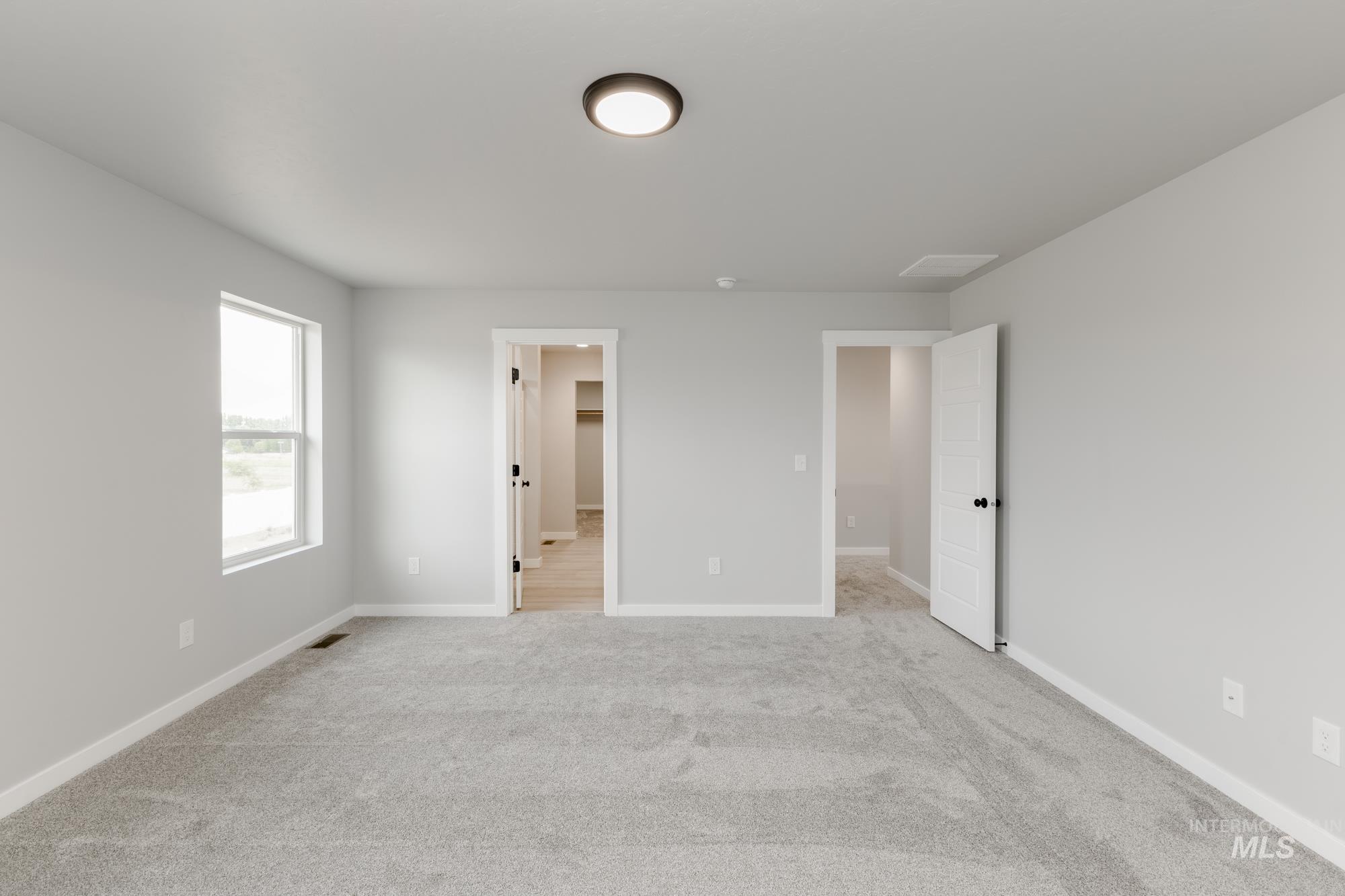 Unfurnished bedroom with light carpet and a spacious closet
