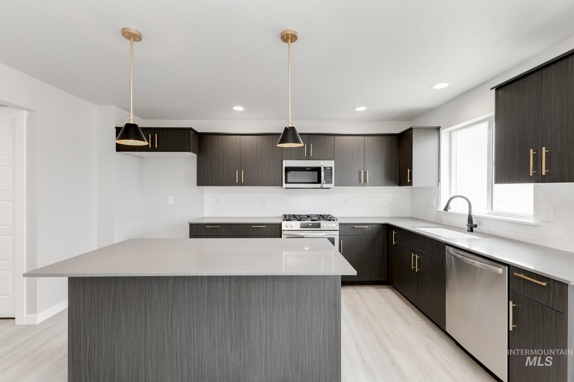 Kitchen with appliances with stainless steel finishes, light wood-type flooring, decorative backsplash, light countertops, and recessed lighting