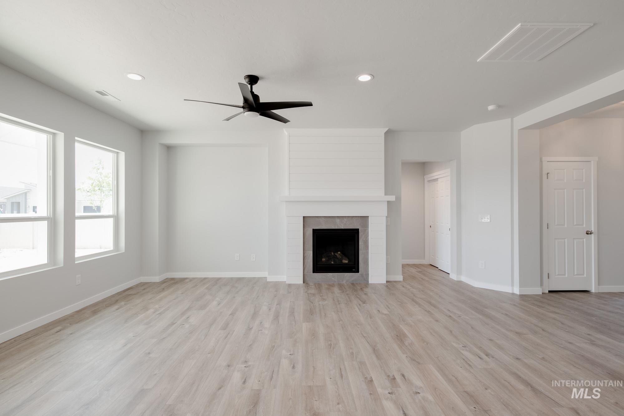 Unfurnished living room with a ceiling fan, a fireplace, light wood finished floors, and recessed lighting