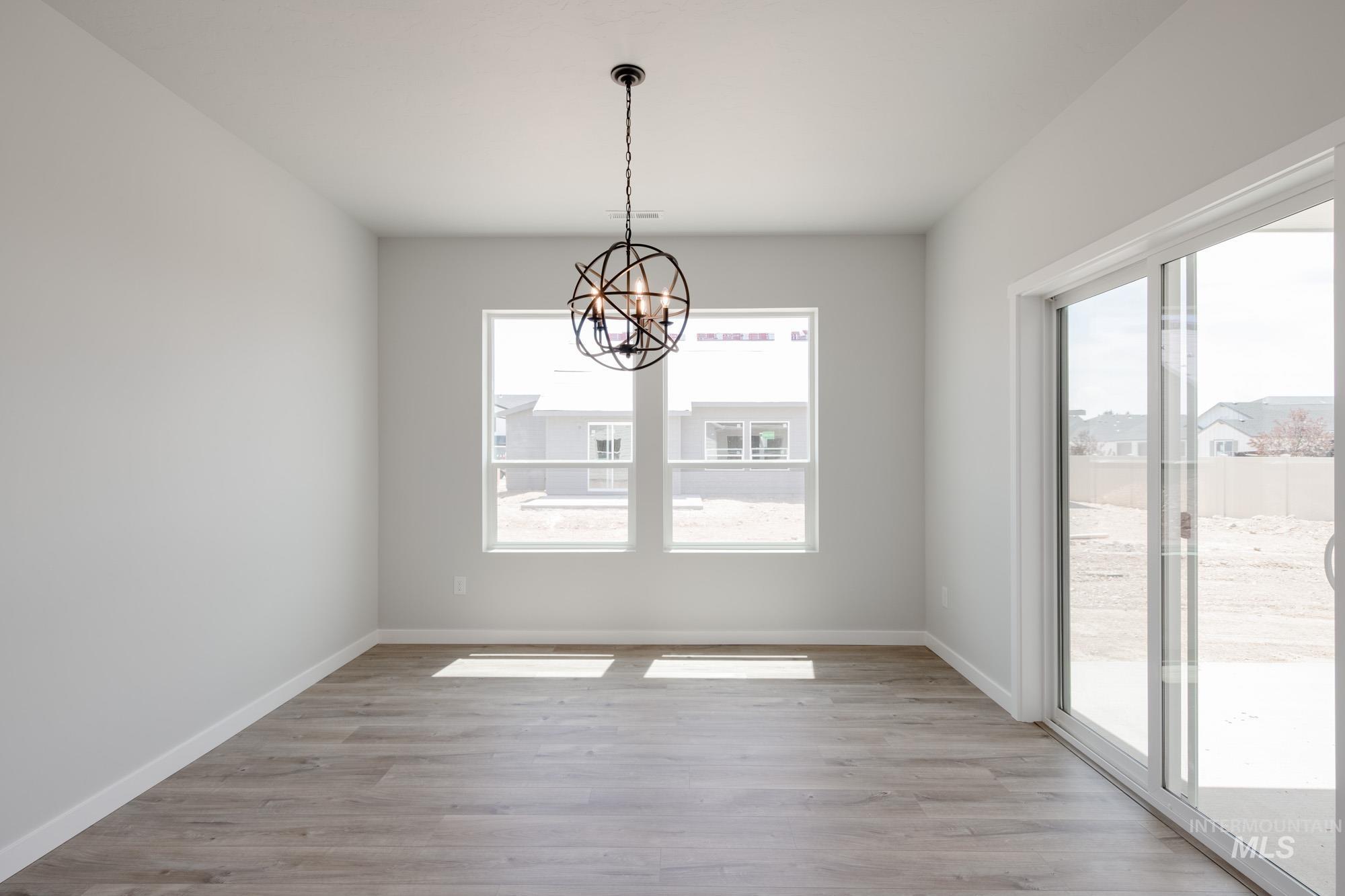 Unfurnished room featuring plenty of natural light, a chandelier, and light wood finished floors