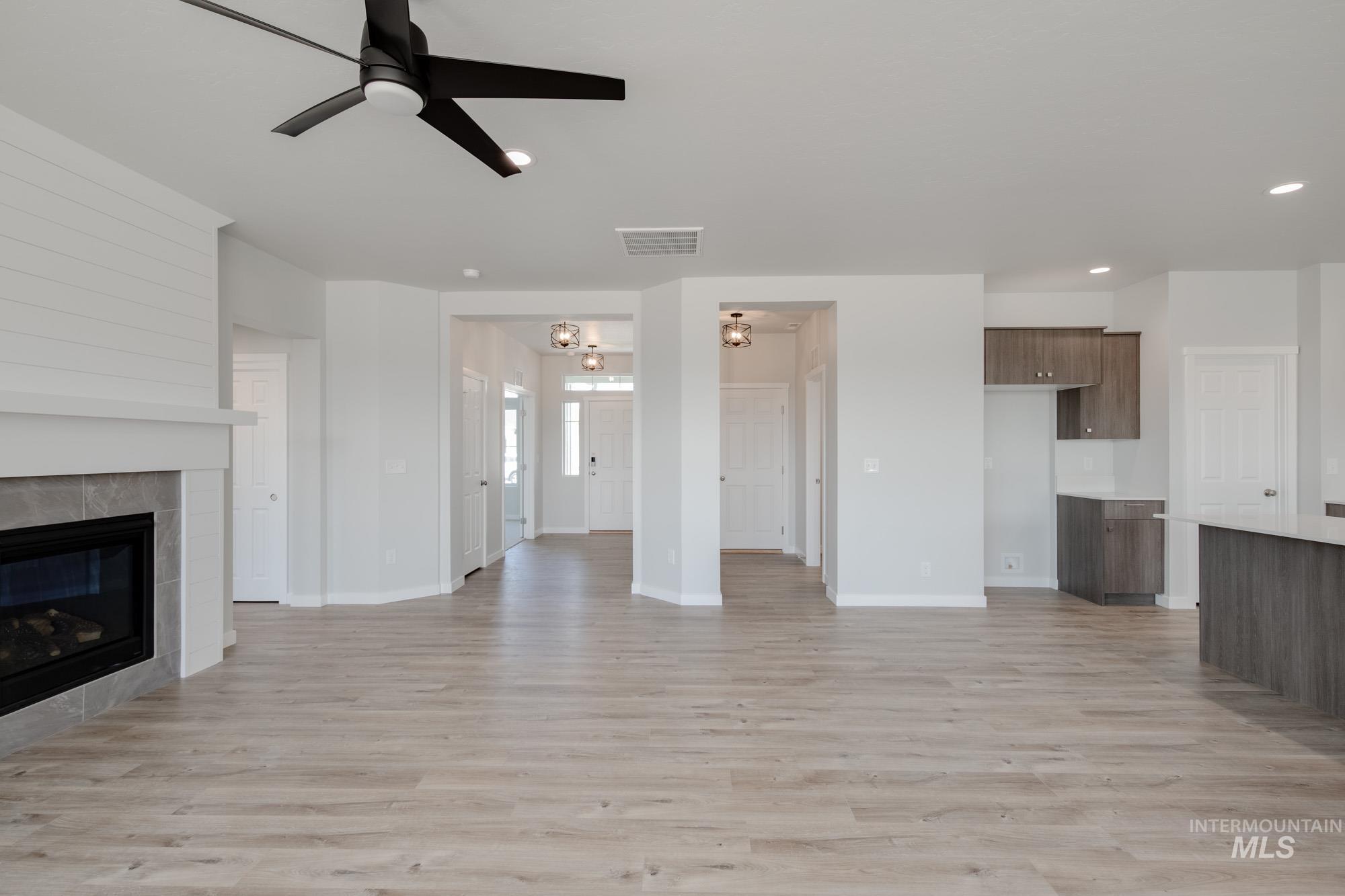 Unfurnished living room featuring ceiling fan, light wood-type flooring, a tile fireplace, and recessed lighting
