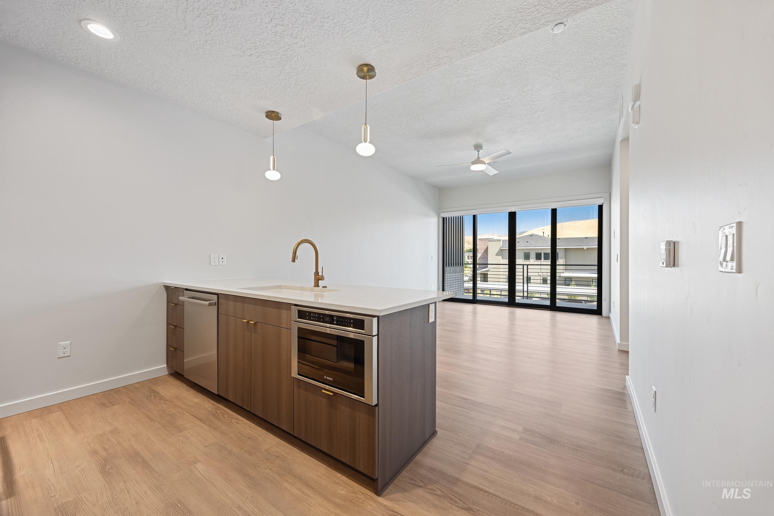 Kitchen featuring a peninsula, modern cabinets, hanging light fixtures, light wood-type flooring, and open floor plan