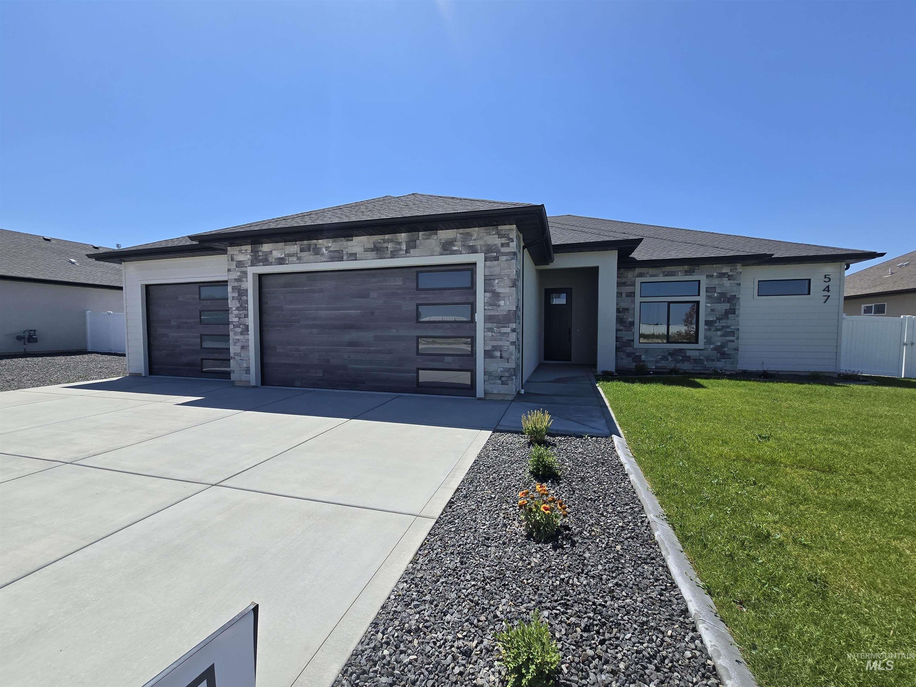 Prairie-style home featuring a garage, concrete driveway, and stone siding