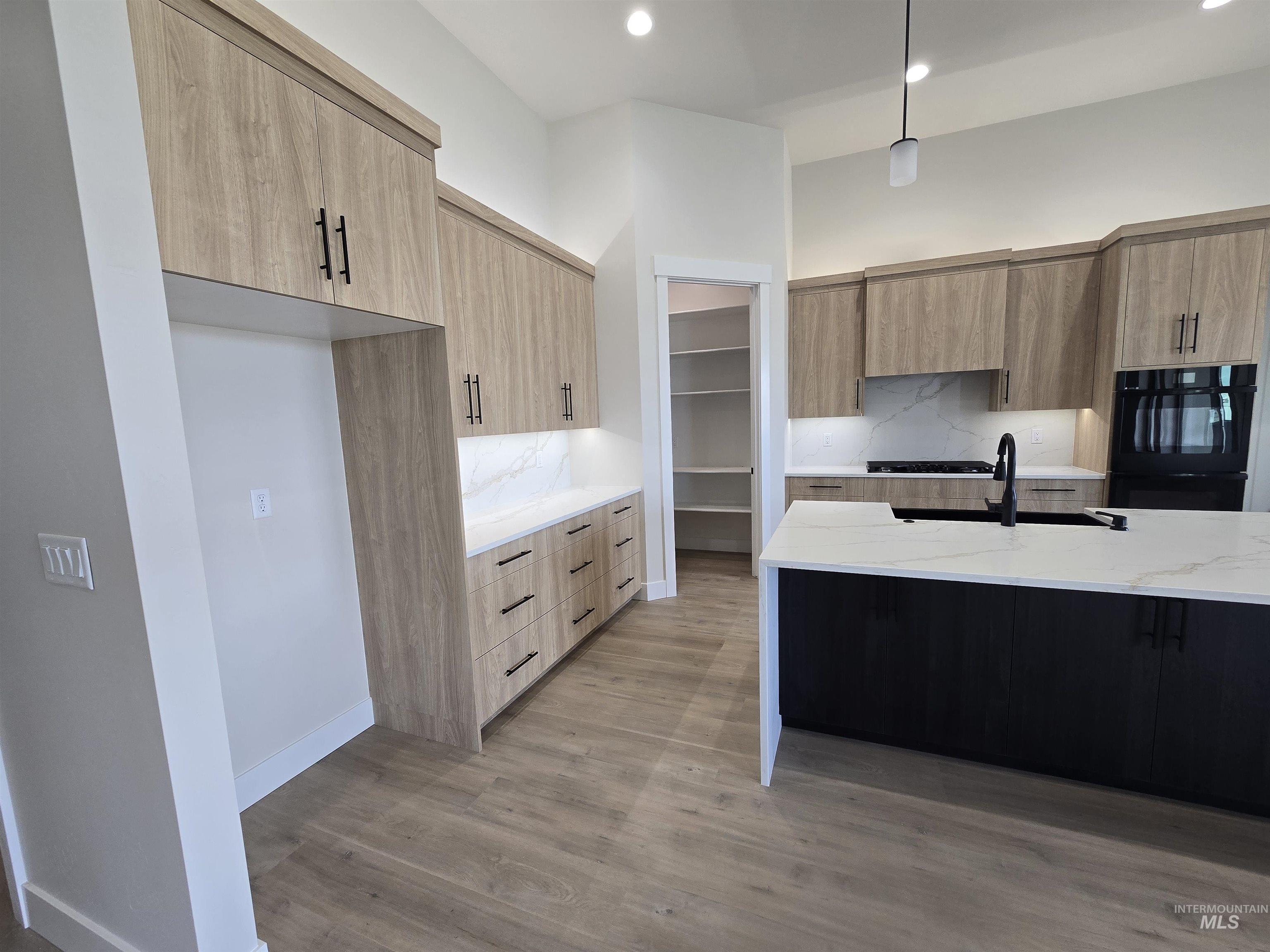 Kitchen featuring modern cabinets, light stone countertops, light brown cabinets, and recessed lighting