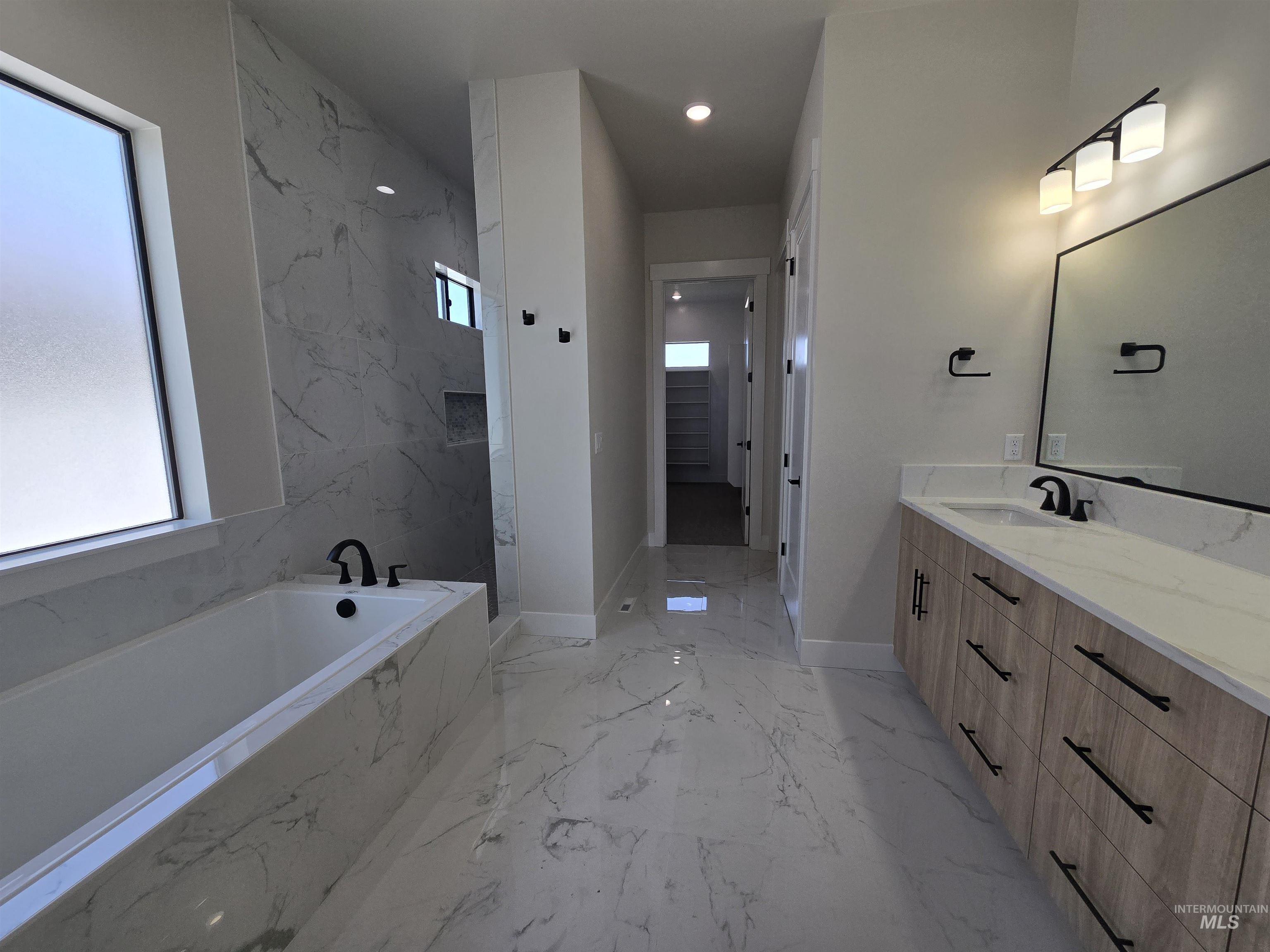 Full bath with marble tiled flooring, vanity, a bath, a marble finish shower, and recessed lighting