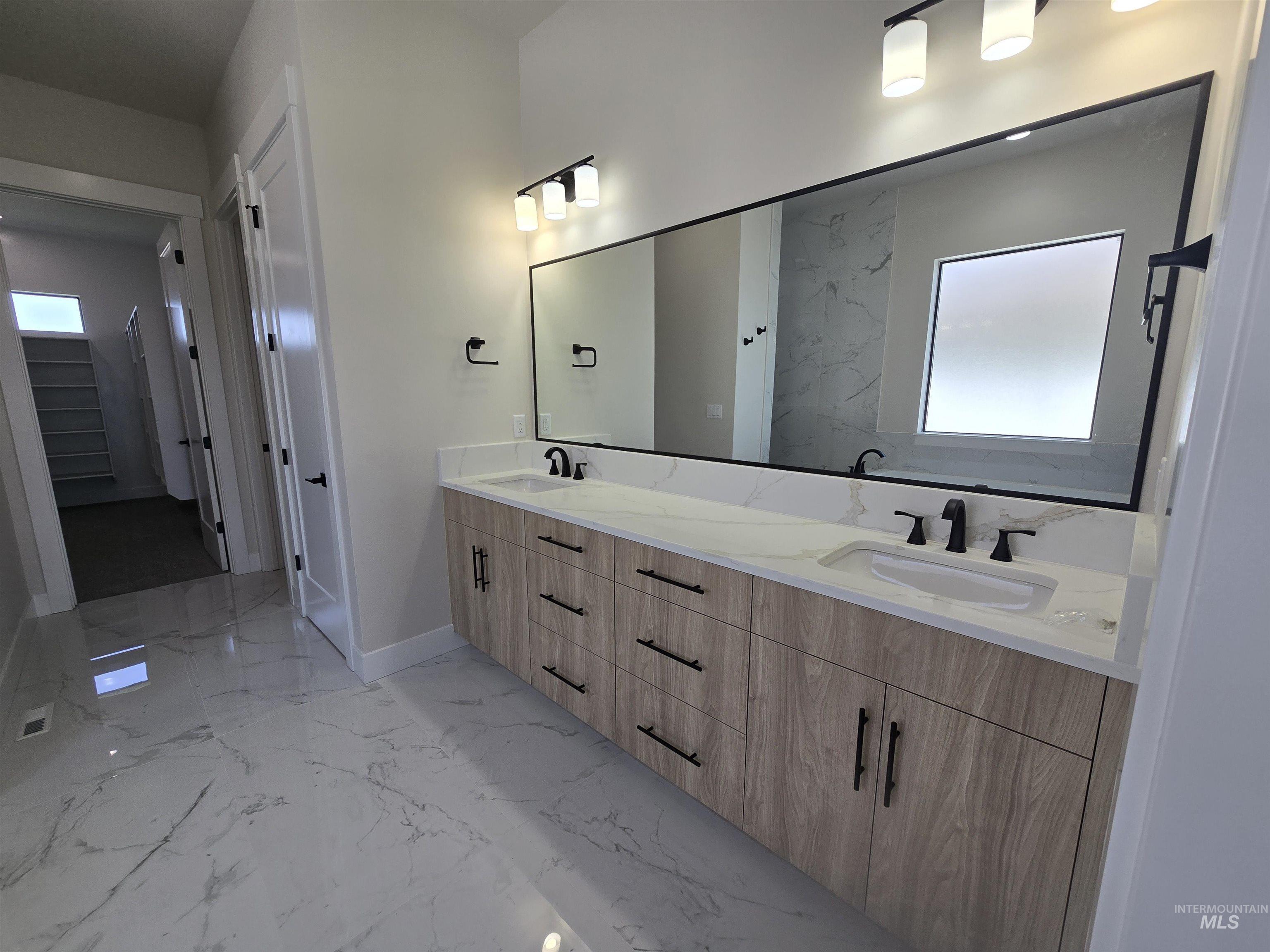 Full bathroom with marble tiled flooring, double vanity, and plenty of natural light