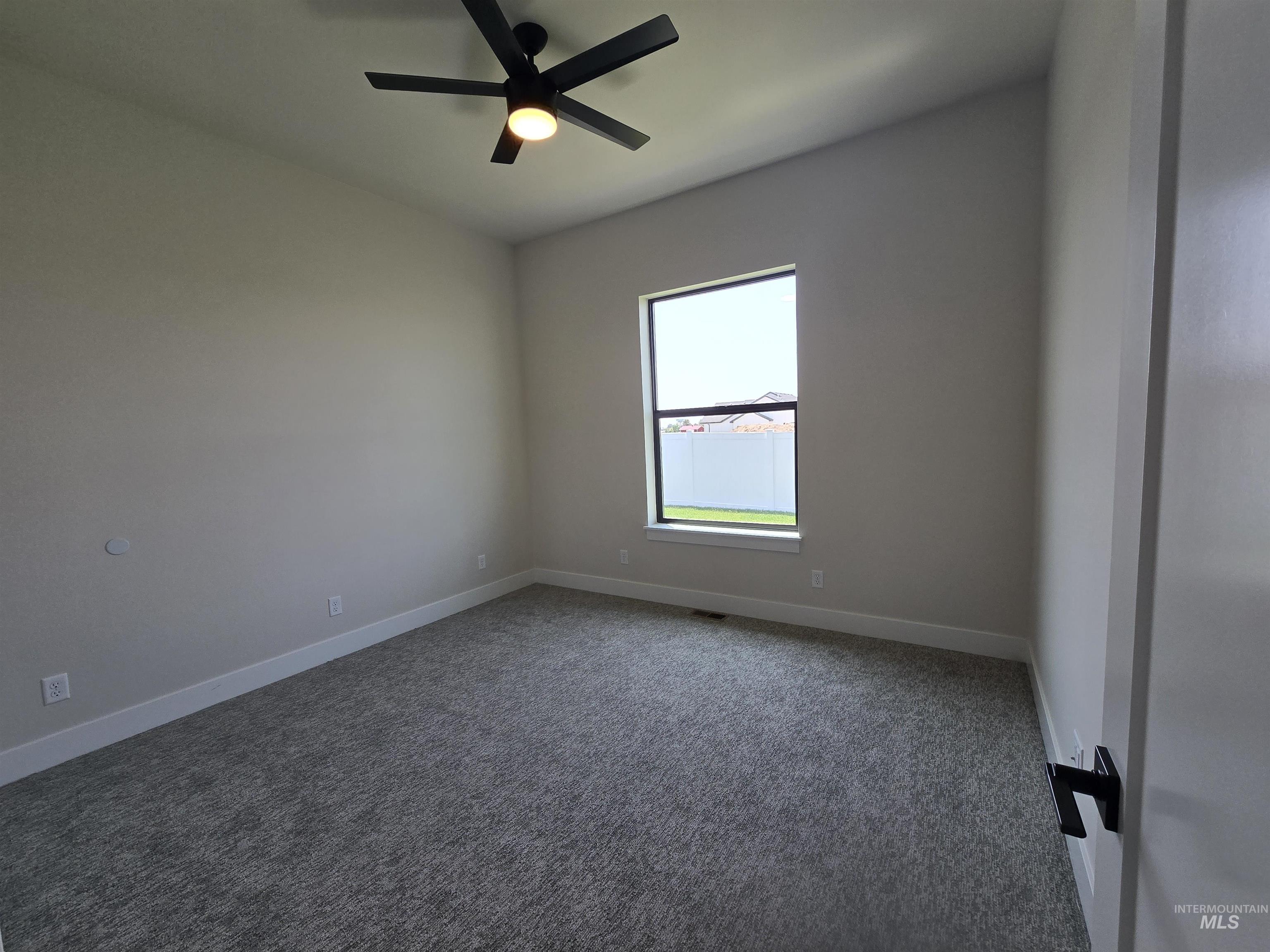 Carpeted empty room featuring baseboards and a ceiling fan