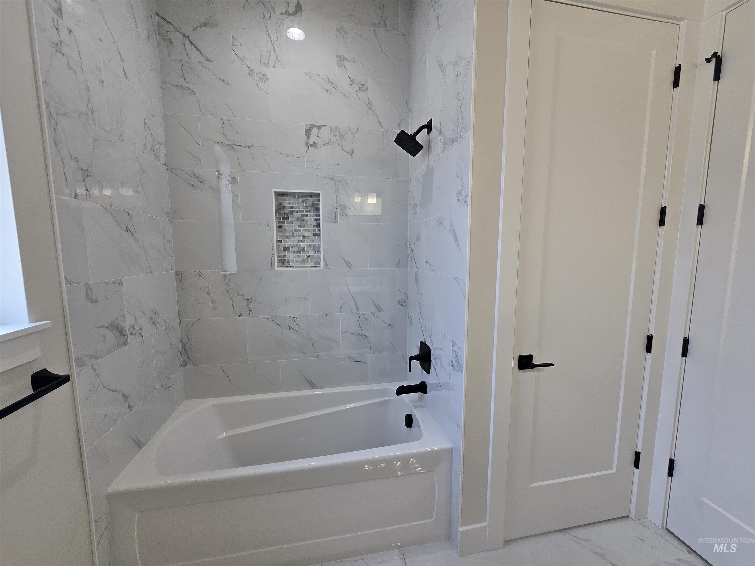 Bathroom featuring shower / tub combination and marble finish flooring