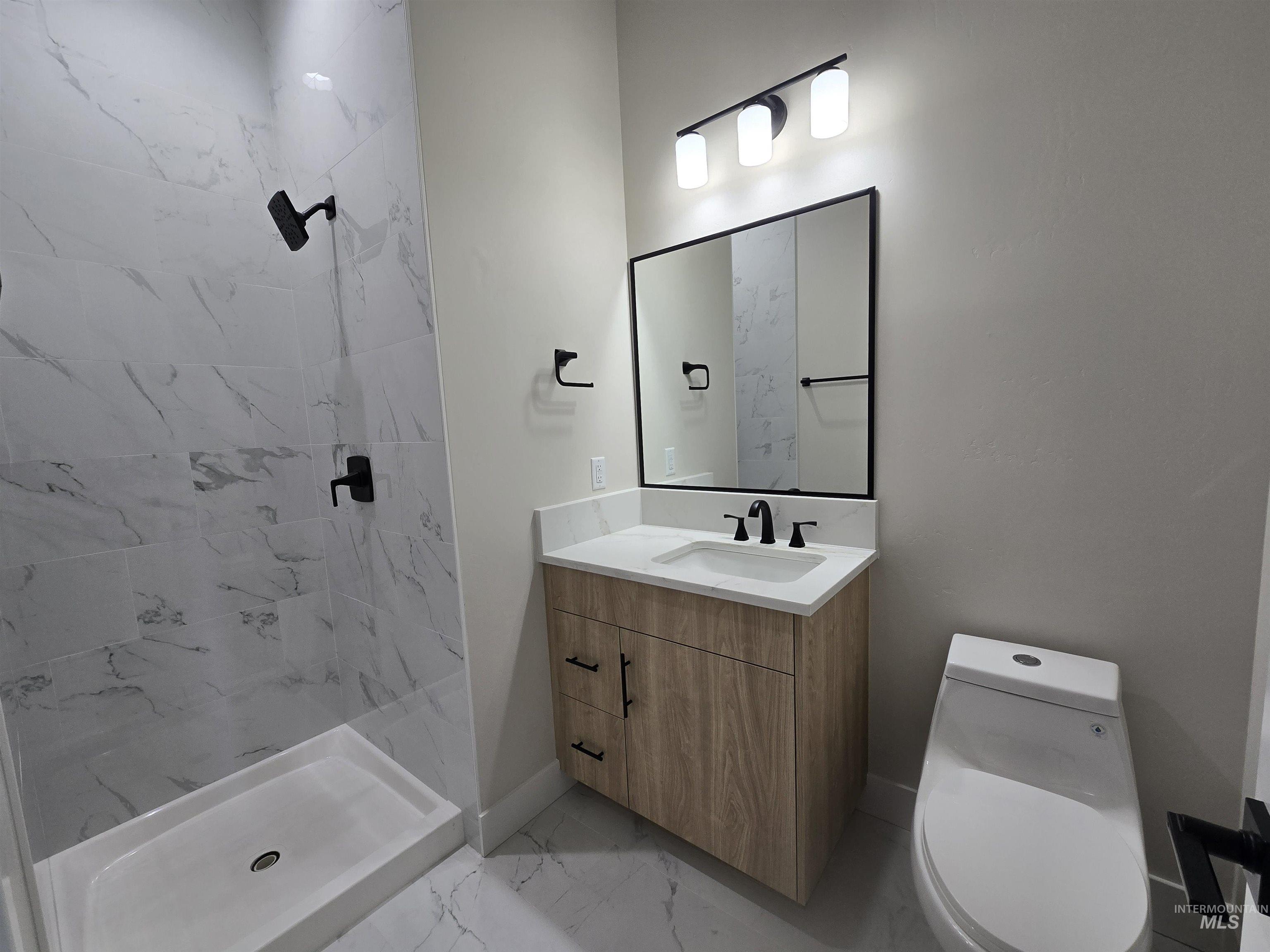 Full bathroom featuring marble finish floors, a stall shower, and vanity