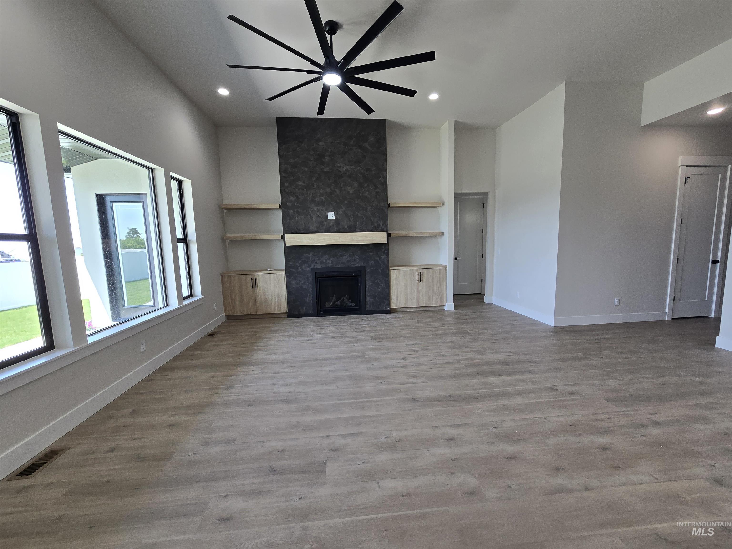 Unfurnished living room with a tiled fireplace, recessed lighting, a ceiling fan, and wood finished floors