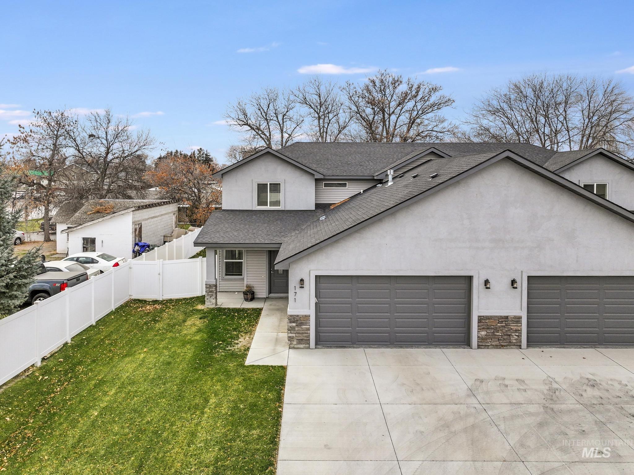 Traditional-style house with a shingled roof, driveway, stucco siding, and stone siding