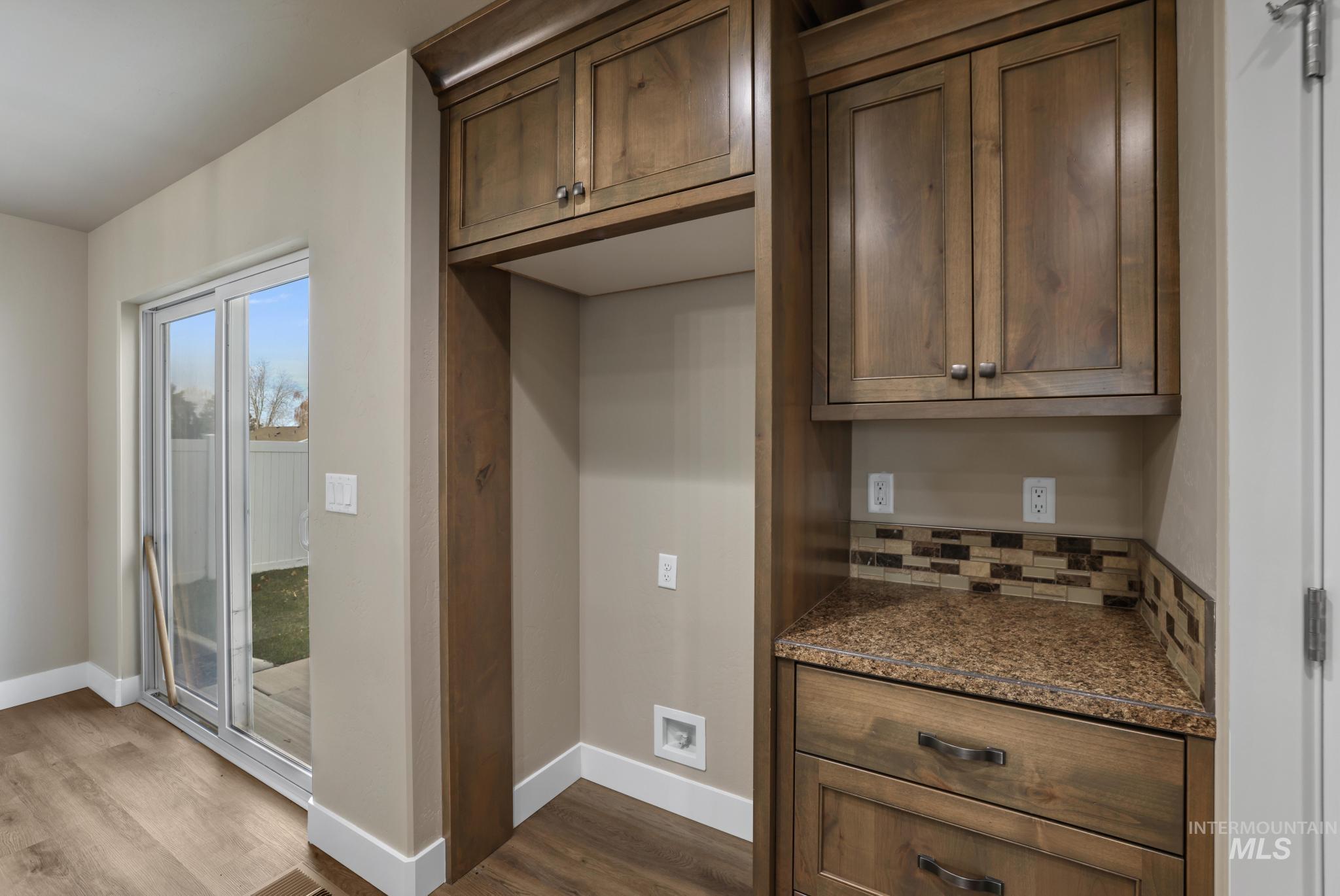 Kitchen featuring dark stone counters, decorative backsplash, dark wood finished floors, and dark brown cabinets