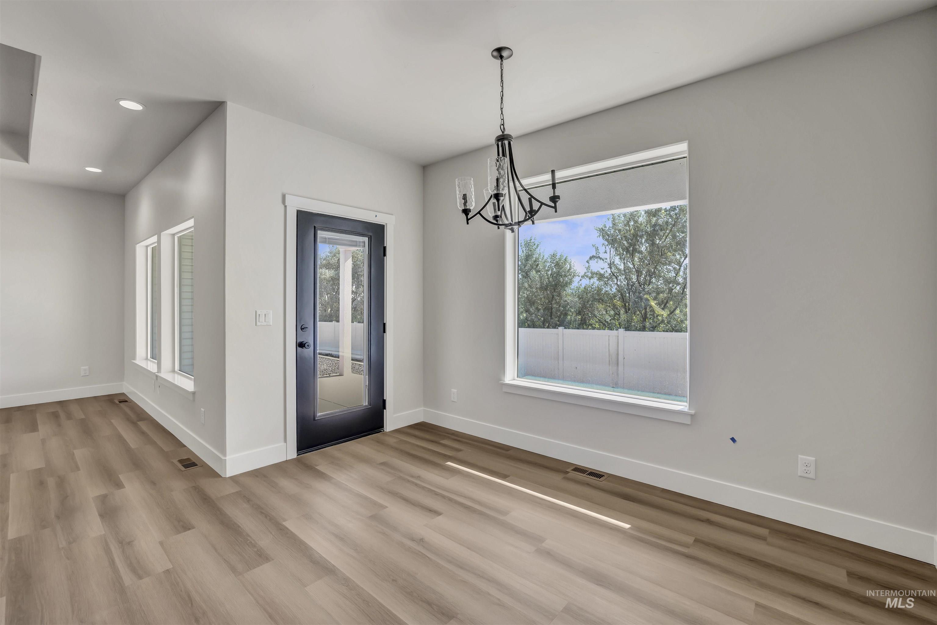 Unfurnished dining area with a chandelier, light wood-style floors, healthy amount of natural light, and recessed lighting