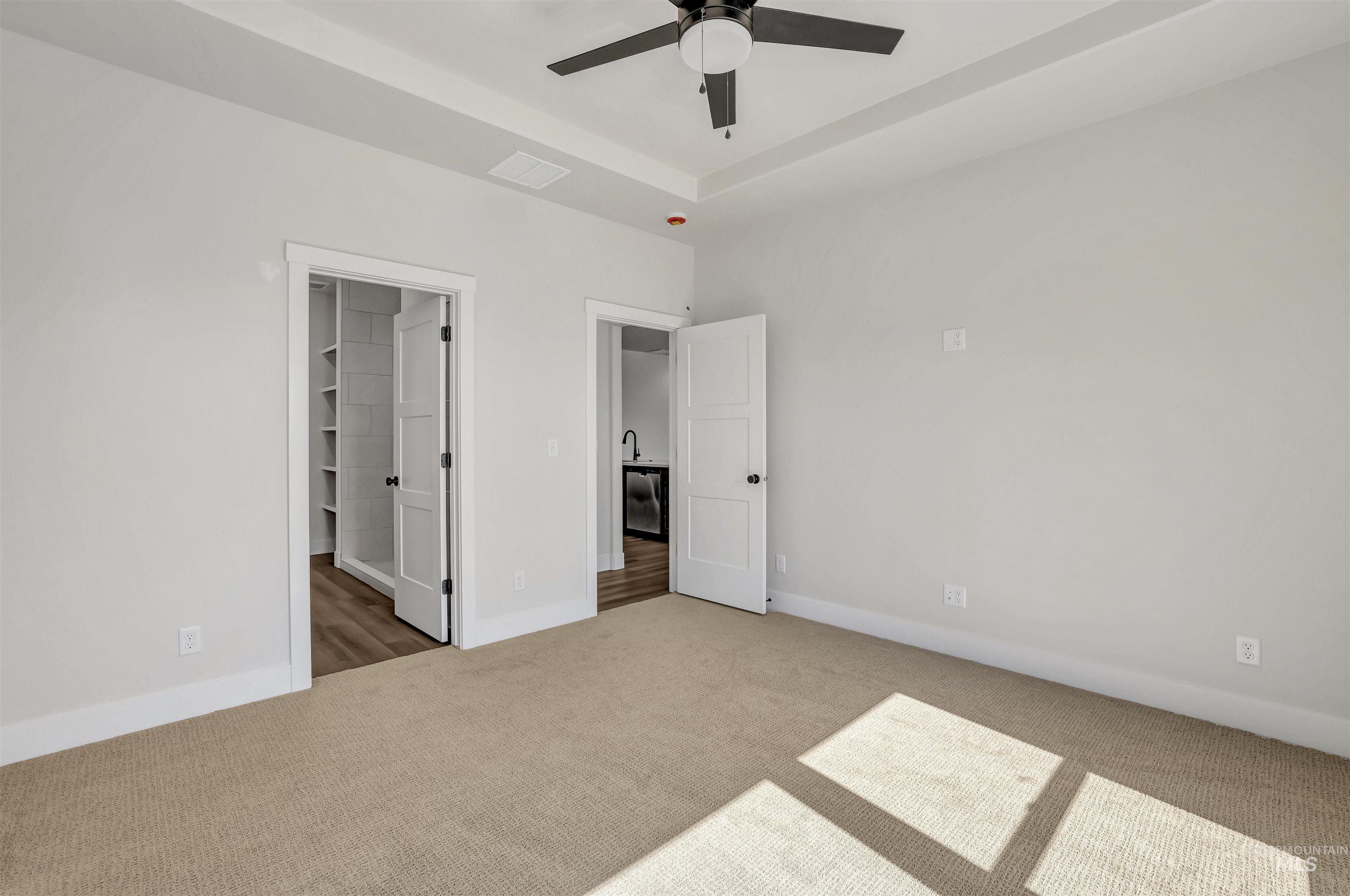 Unfurnished bedroom with carpet floors, a spacious closet, and a ceiling fan