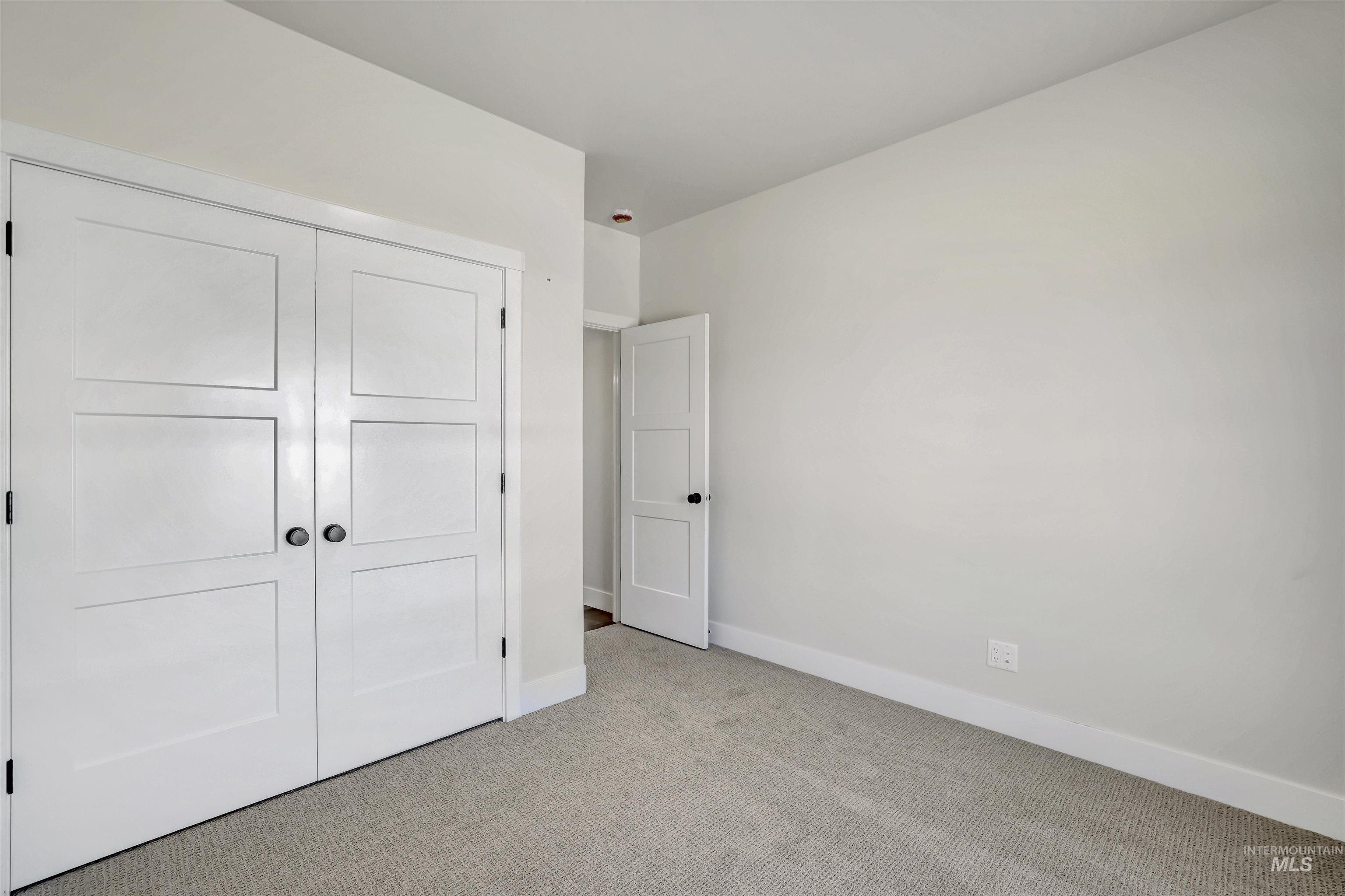 Unfurnished bedroom featuring light carpet and a closet
