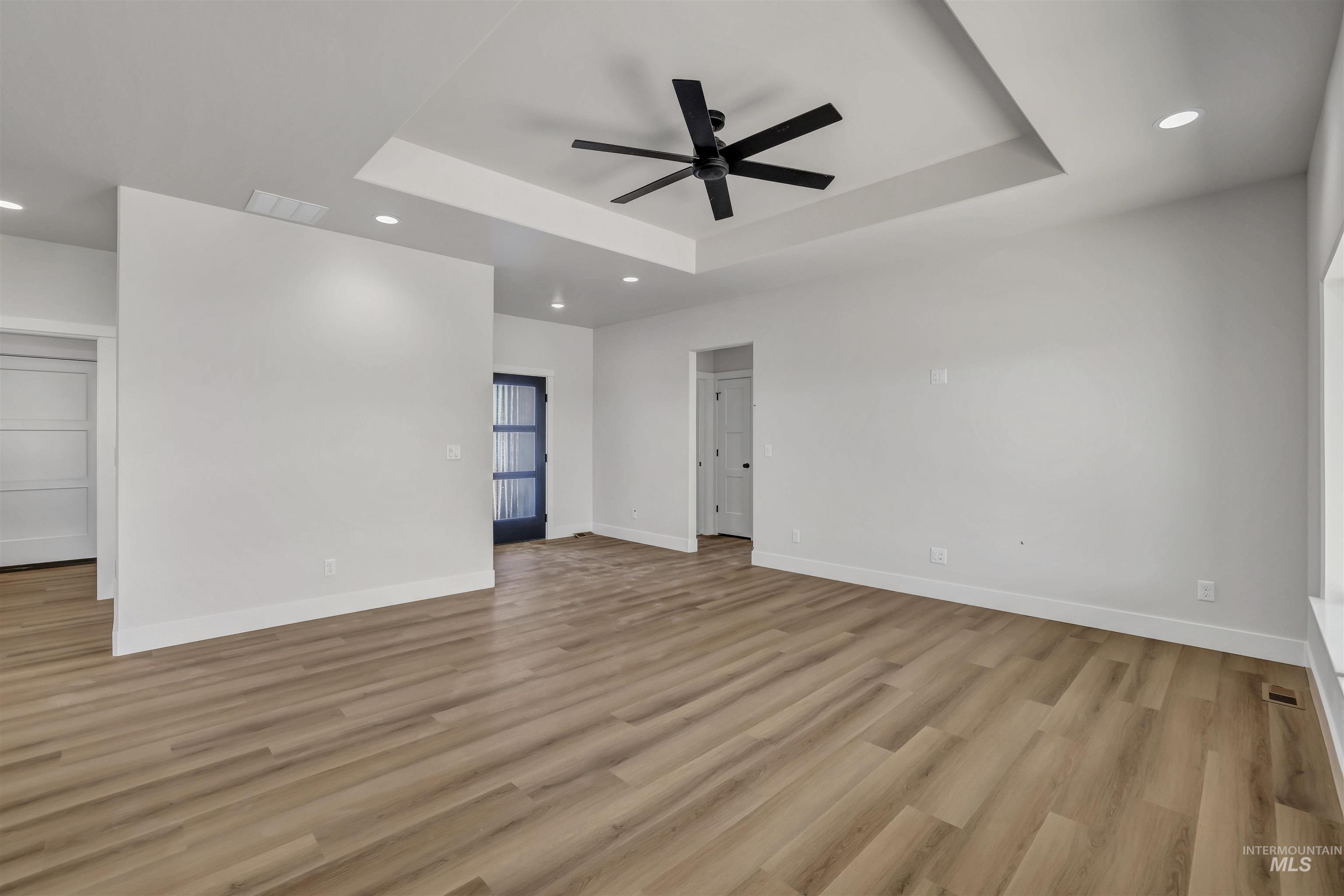 Spare room featuring a tray ceiling, ceiling fan, recessed lighting, and light wood-style floors