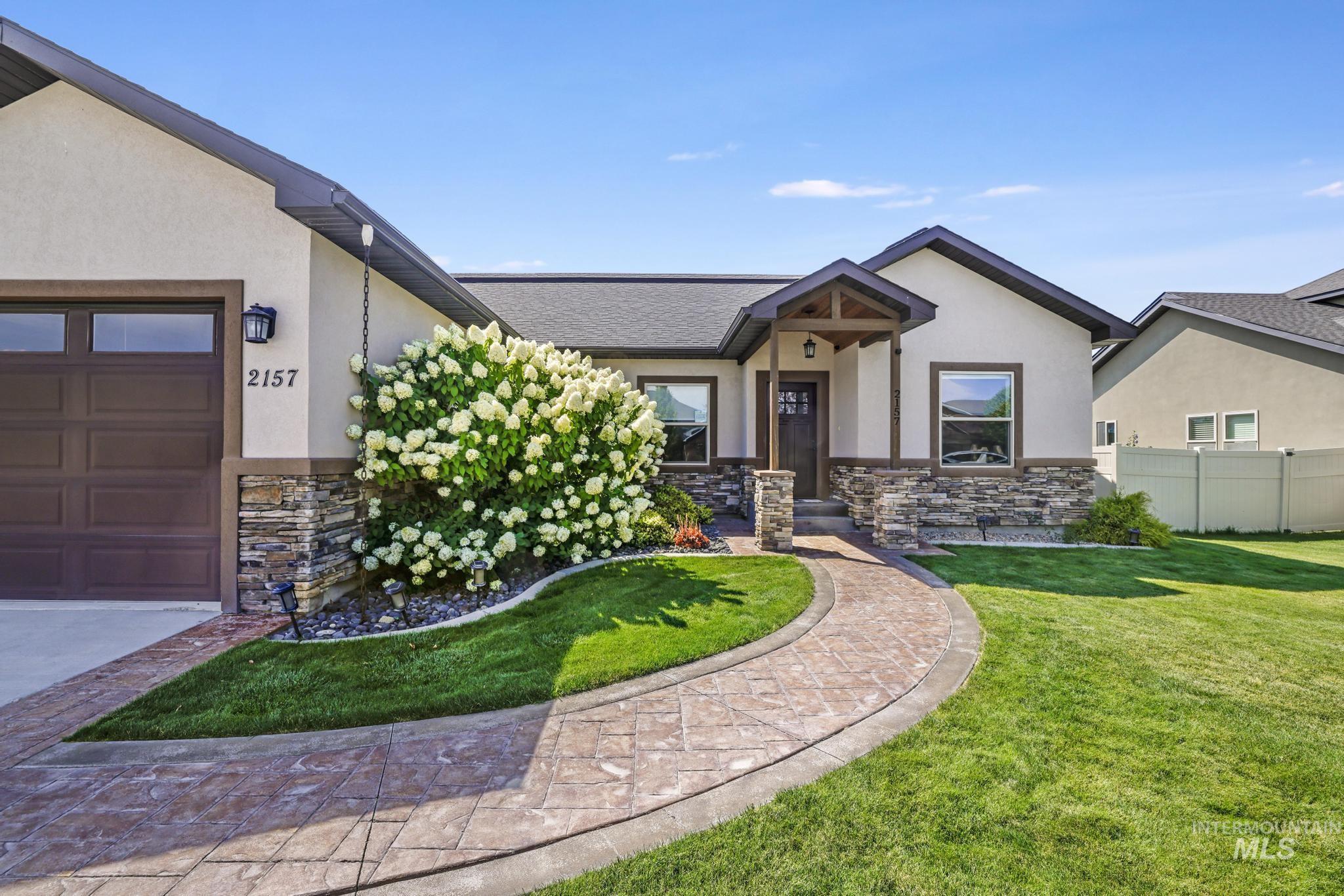 View of front of home with stone siding, an attached garage, and stucco siding