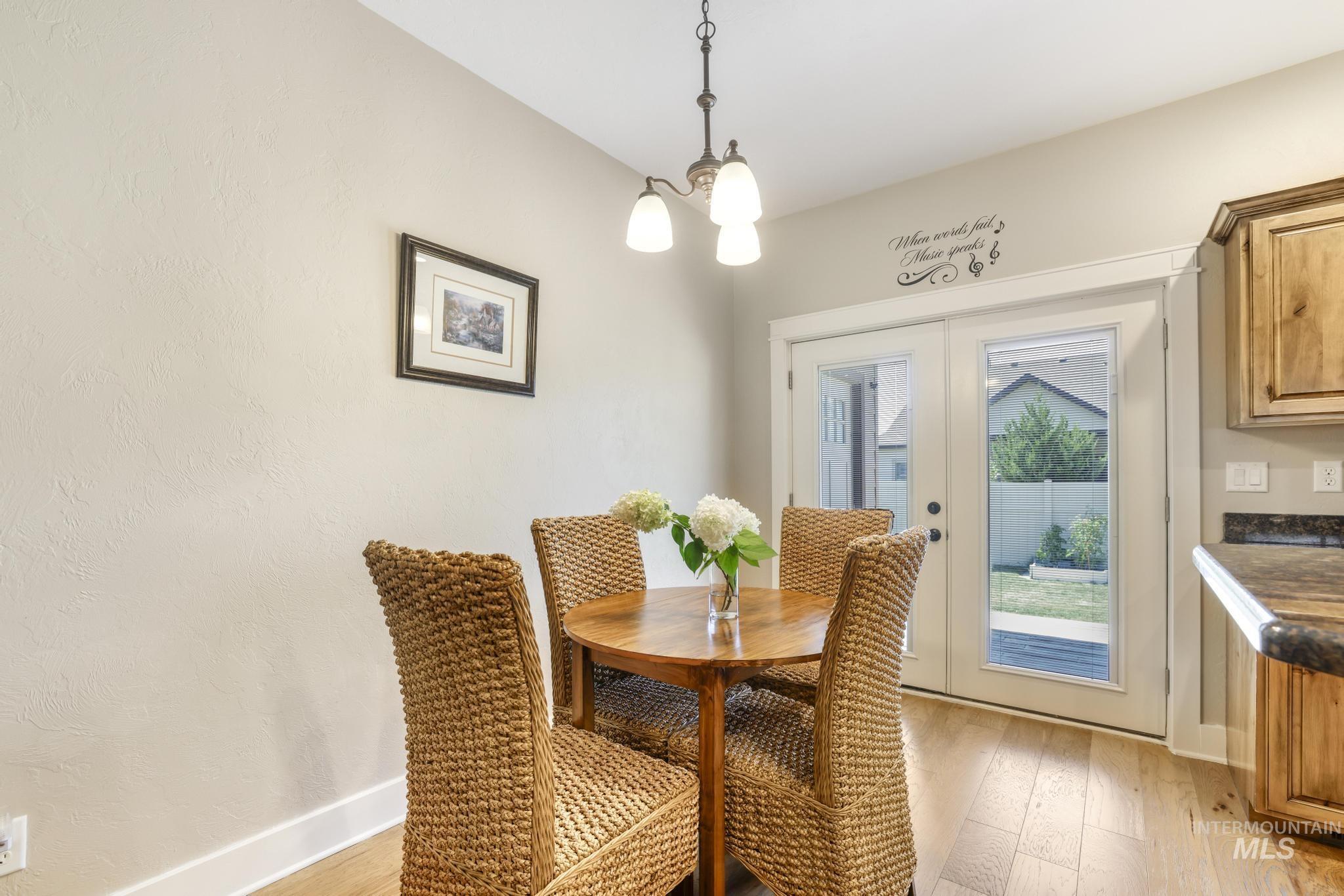 Dining space with french doors, light wood-style flooring, and a chandelier