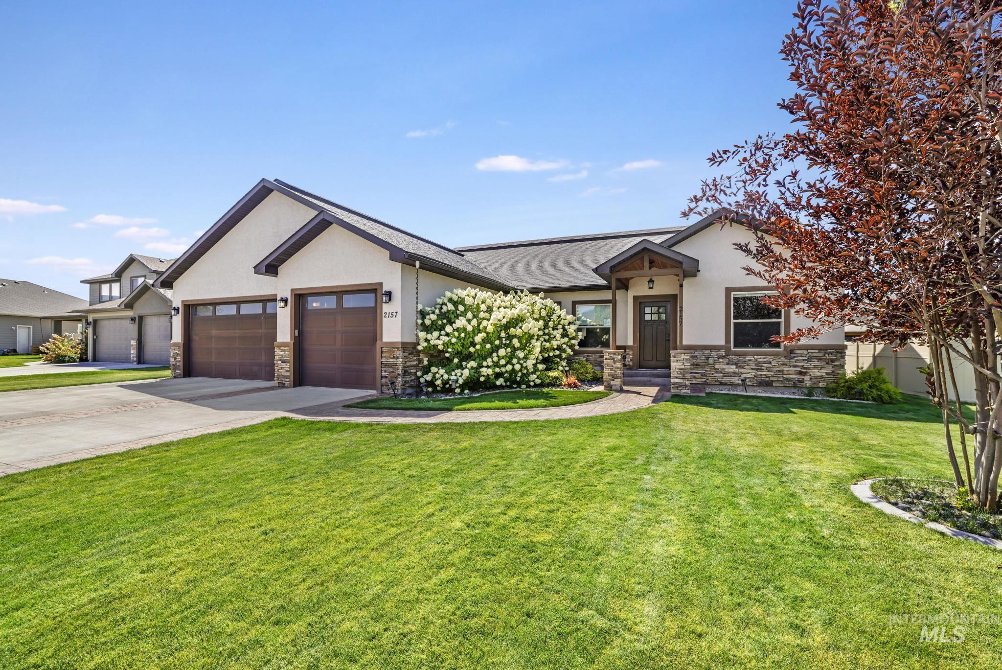 View of front facade with stone siding, an attached garage, stucco siding, a front yard, and concrete driveway