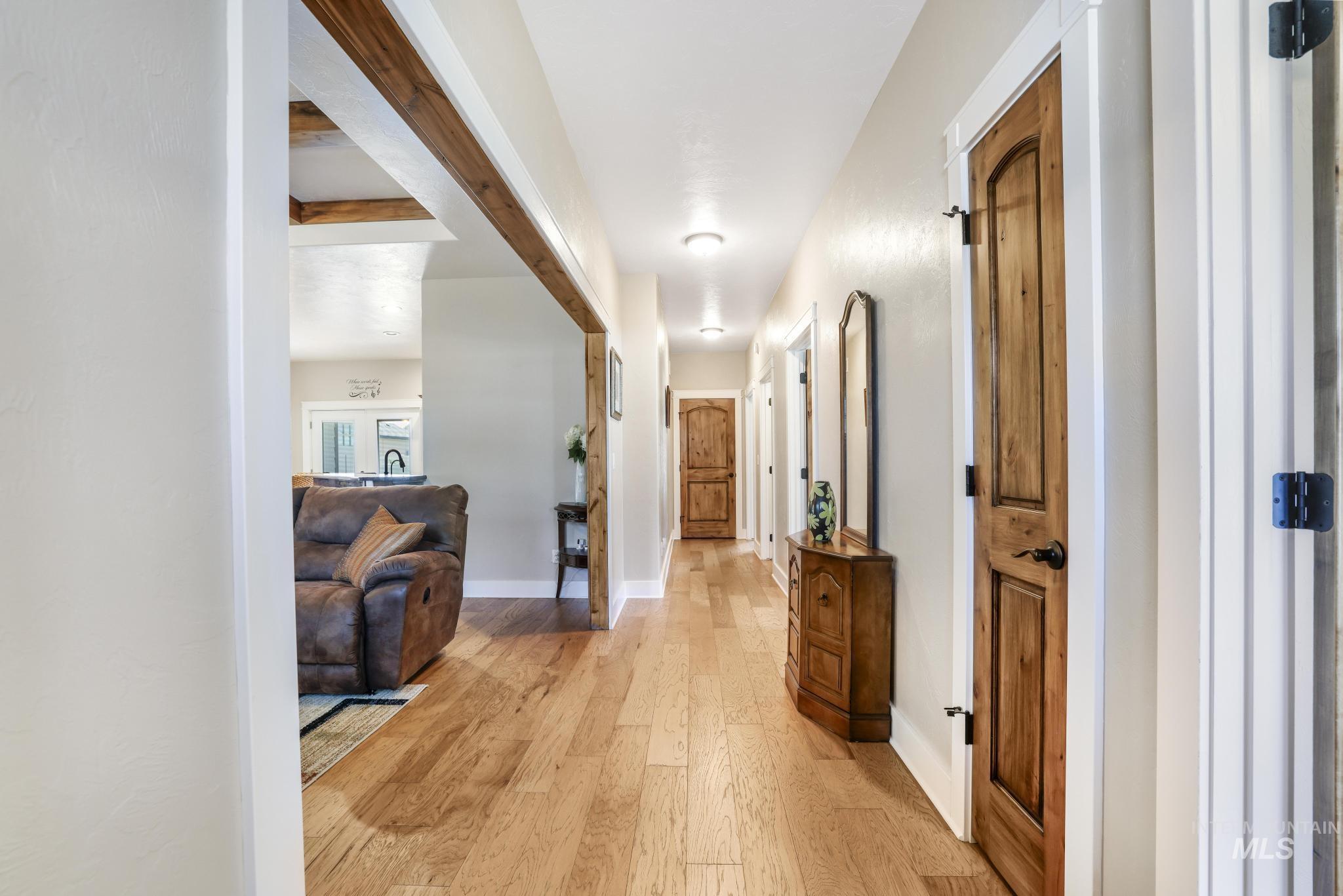 Corridor featuring light wood-style floors and beamed ceiling