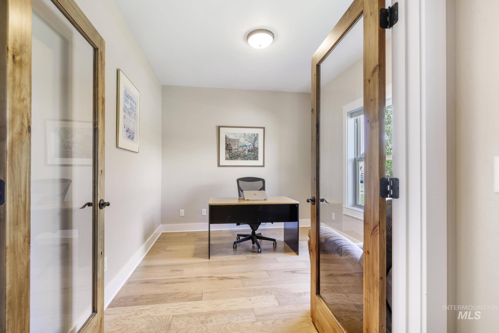 Home office with light wood finished floors and french doors