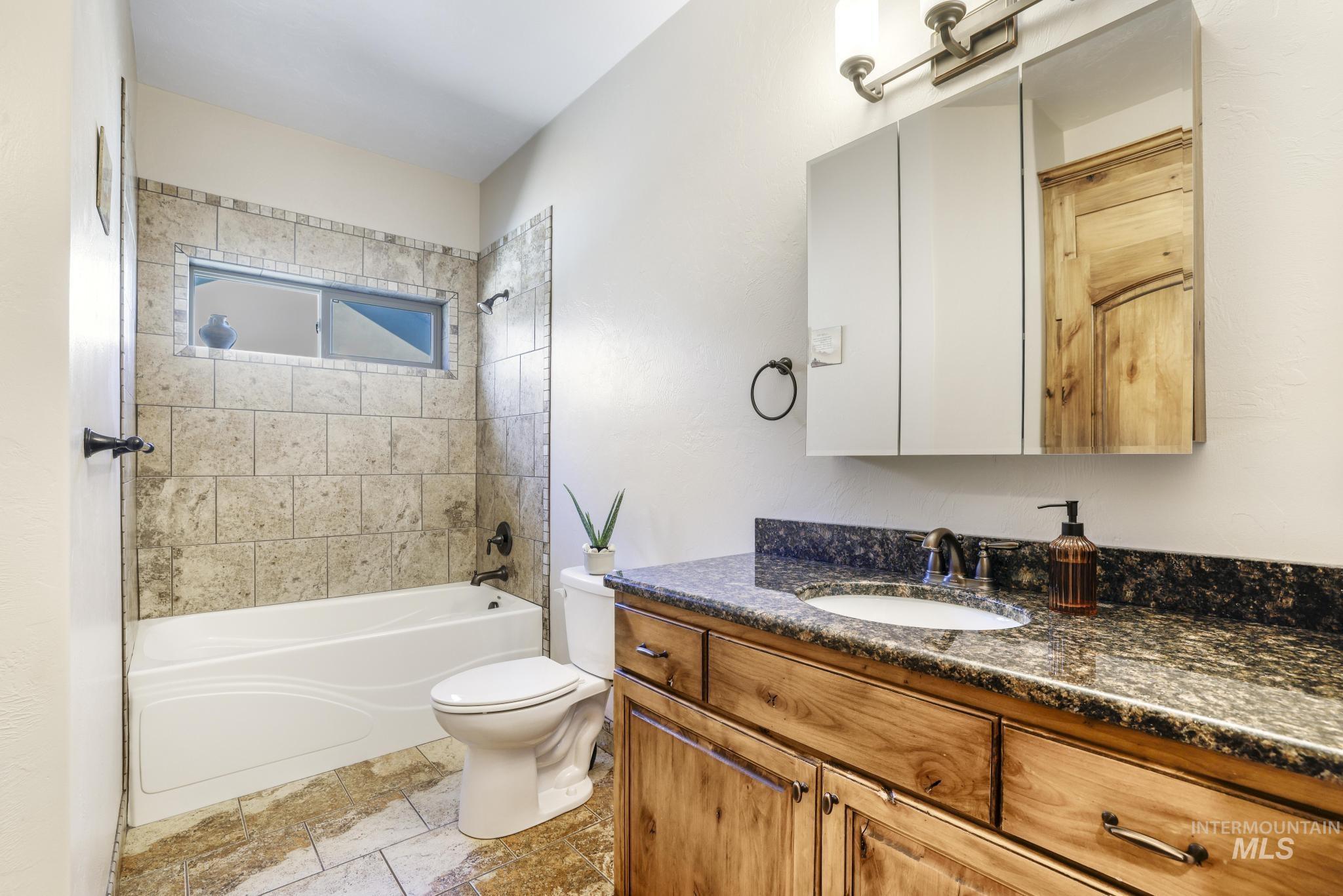 Bathroom featuring  shower combination, vanity, and stone tile floors