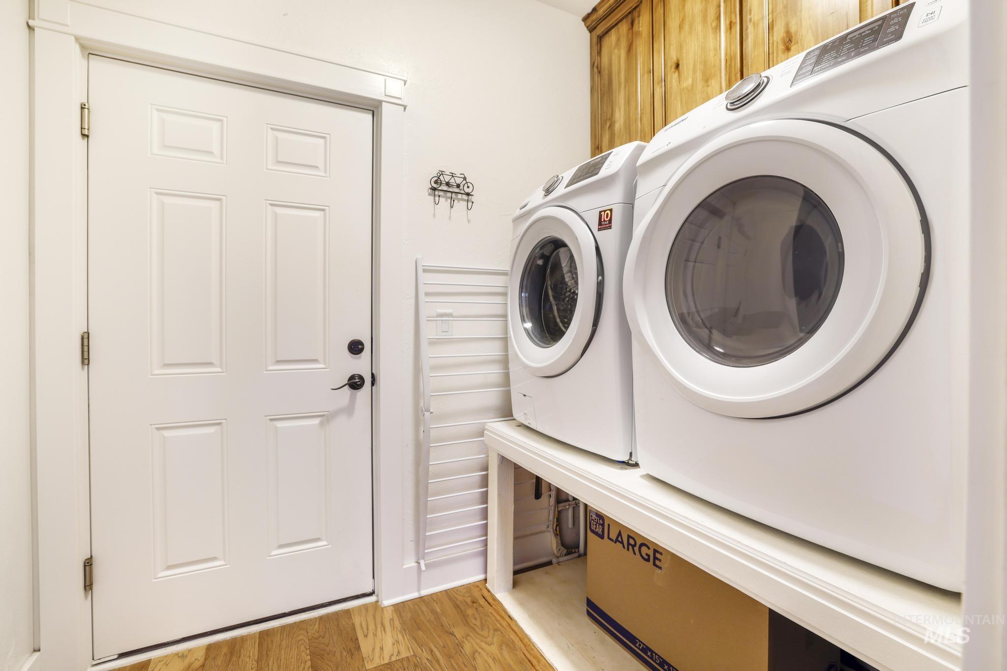 Laundry area with light wood-type flooring, cabinet space, and washer and clothes dryer