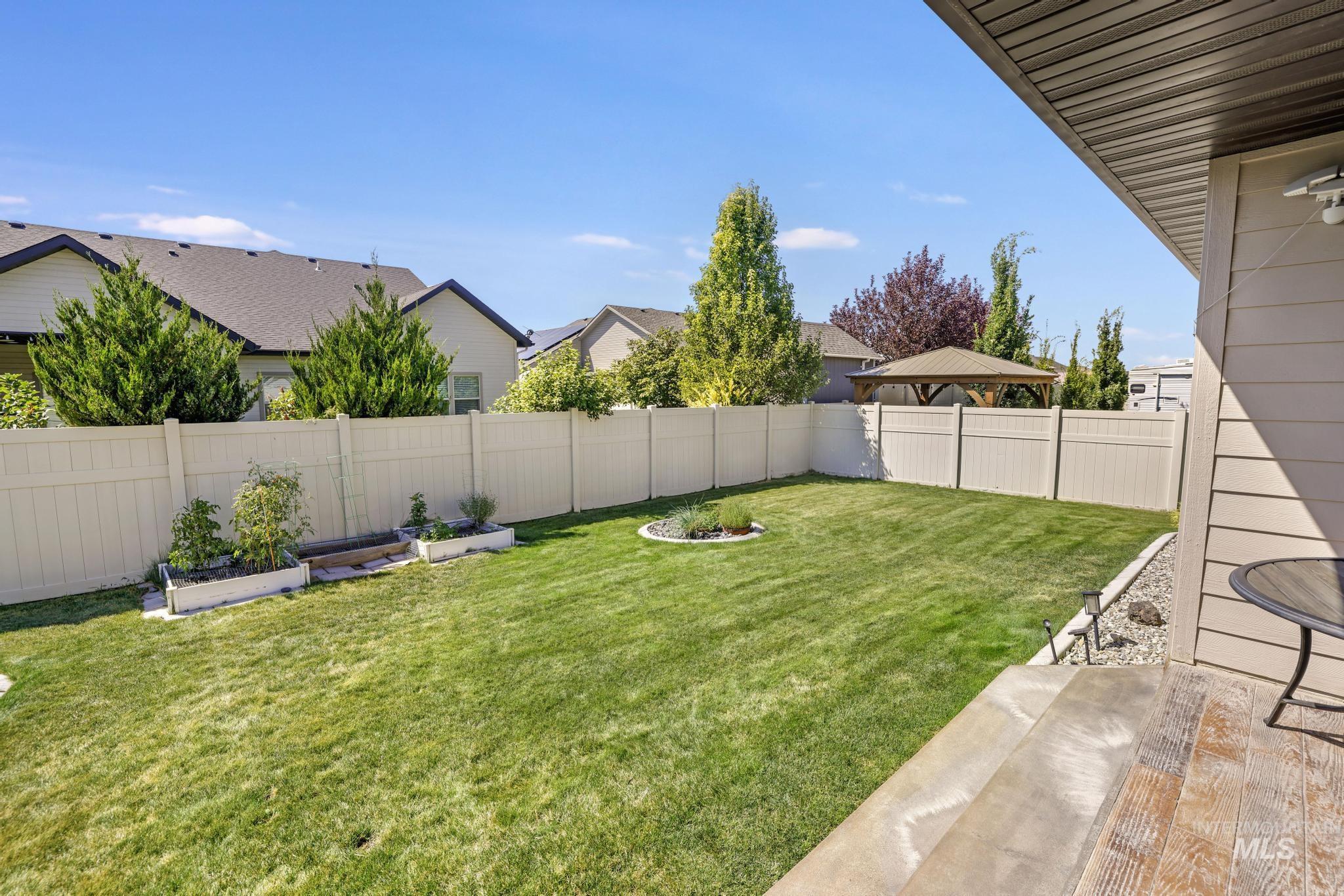 Fenced backyard featuring a patio area and a vegetable garden