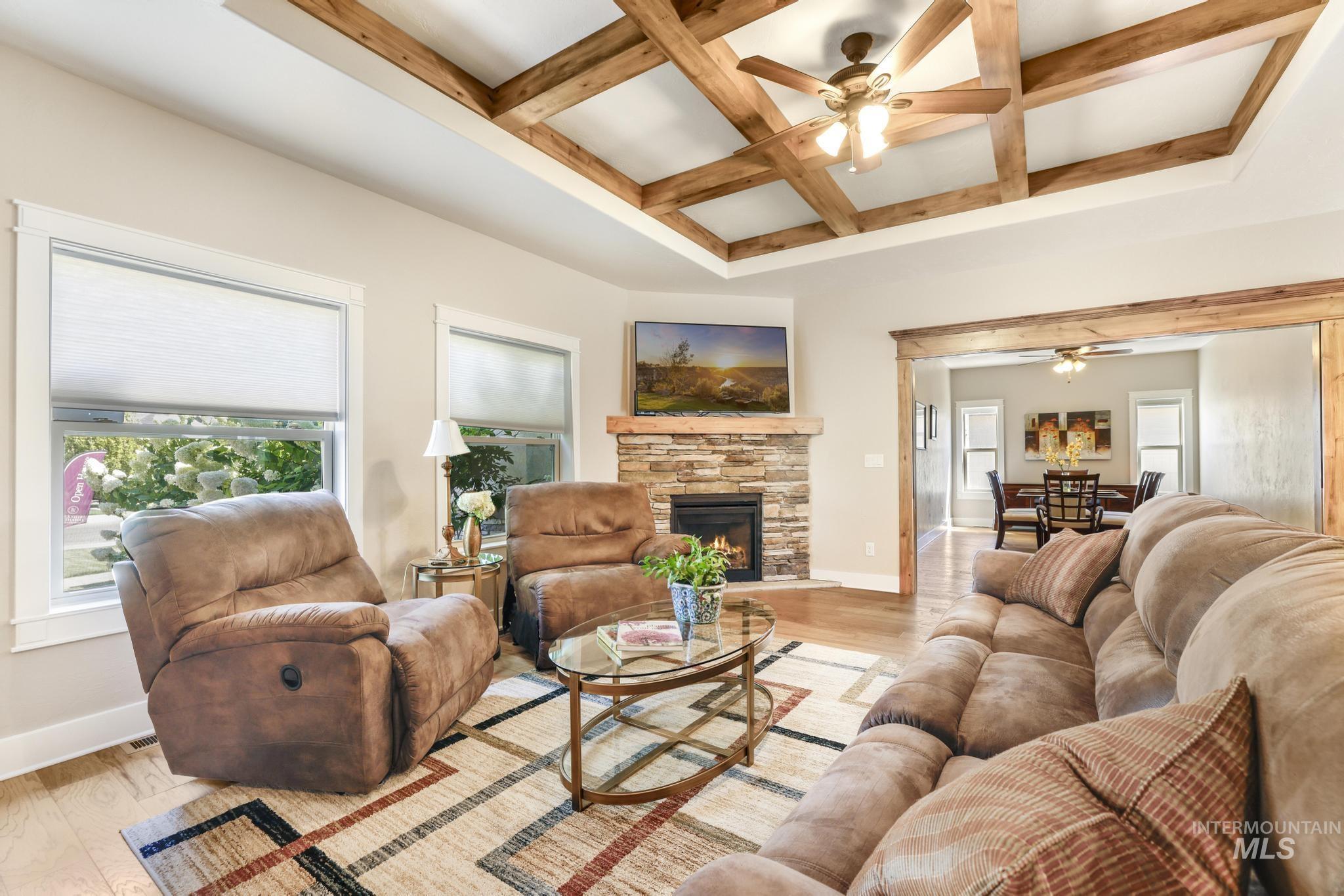 Living area with coffered ceiling, plenty of natural light, a ceiling fan, beamed ceiling, and light wood-type flooring