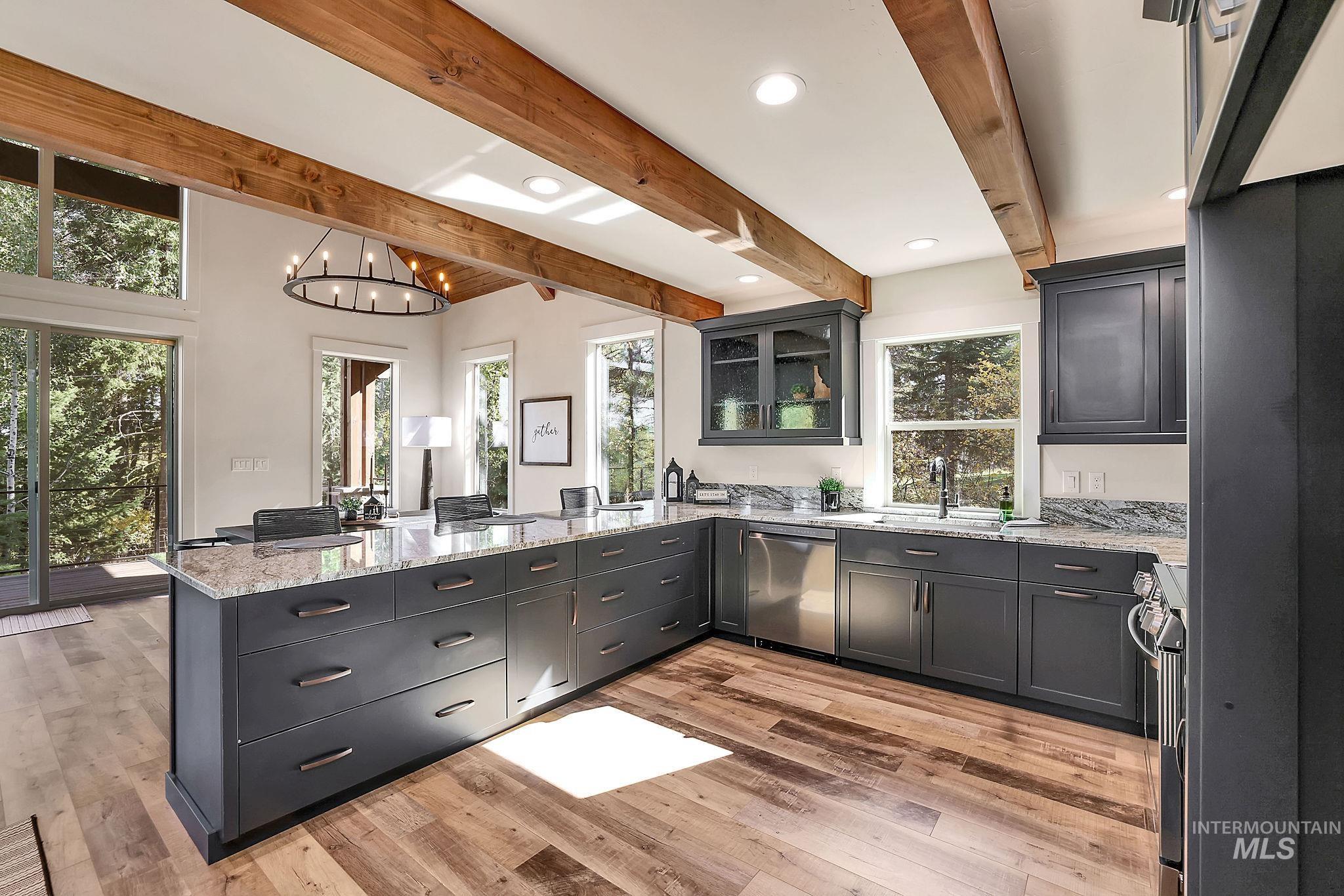 Kitchen featuring light stone counters, glass insert cabinets, recessed lighting, beamed ceiling, and stainless steel appliances