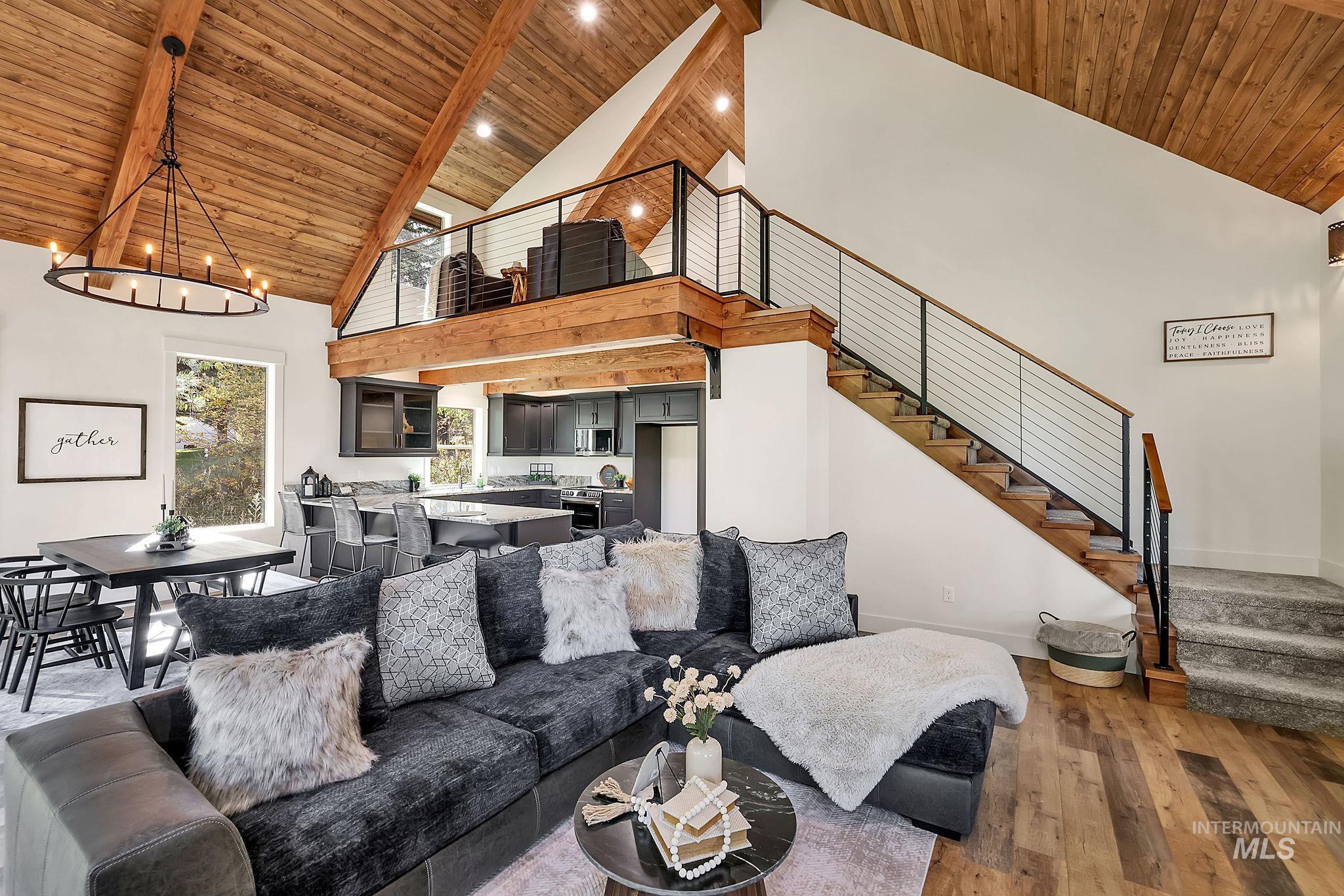 Living room featuring high vaulted ceiling, a wood ceiling with exposed beams, dark wood finished floors, stairs, and a chandelier