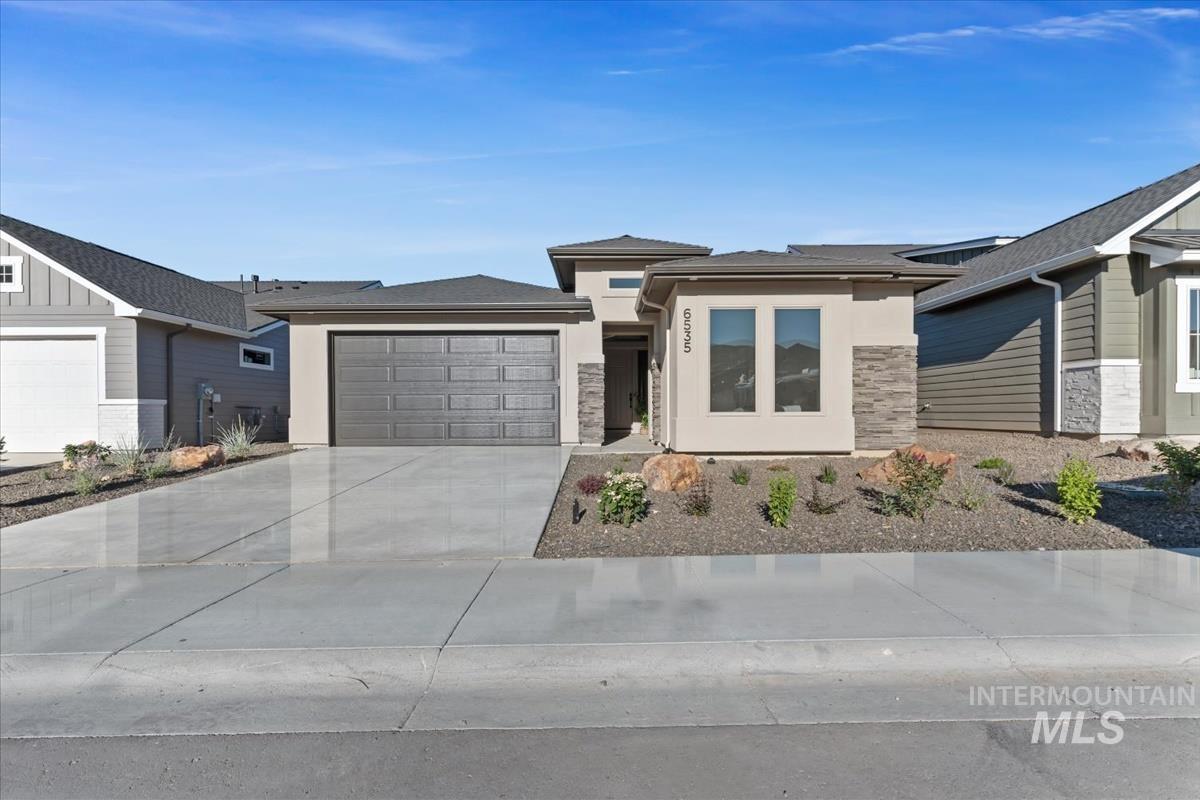 Prairie-style house featuring a garage, concrete driveway, and stucco siding