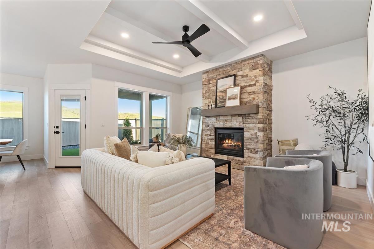 Living room with a raised ceiling, light wood-style flooring, healthy amount of natural light, and recessed lighting