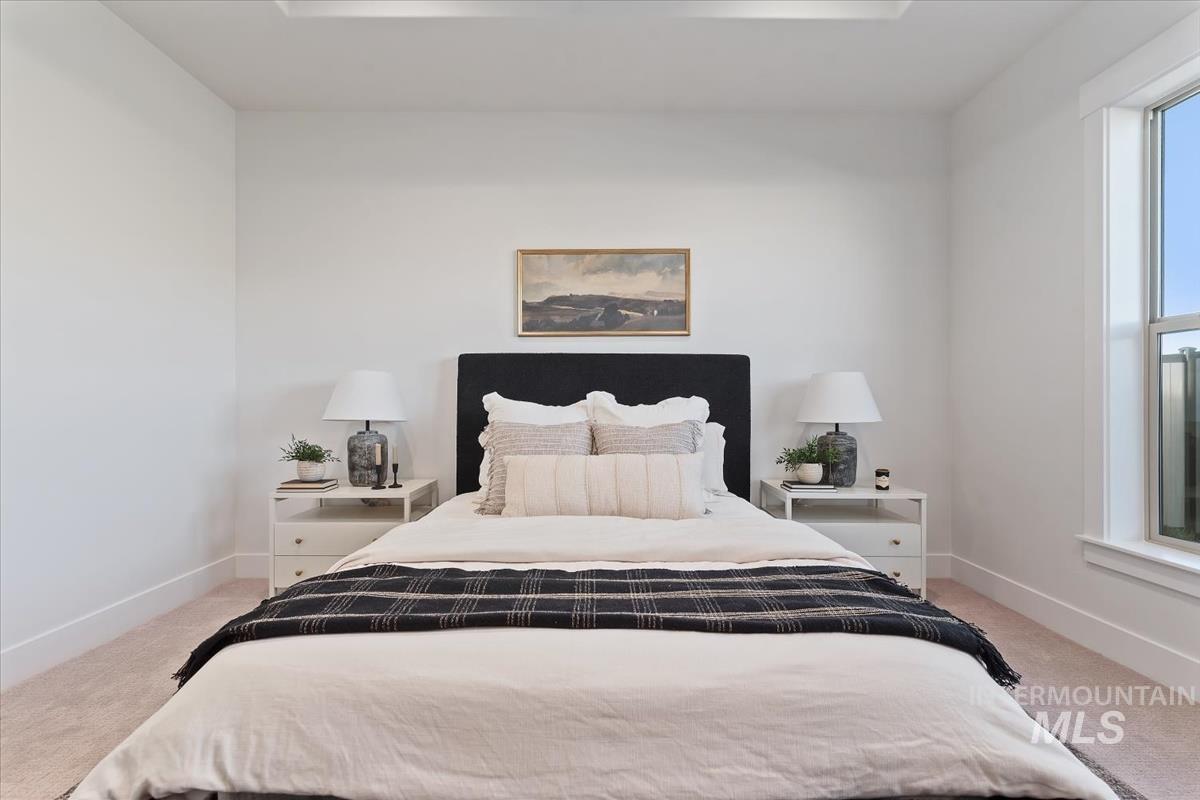 Bedroom featuring light carpet and baseboards