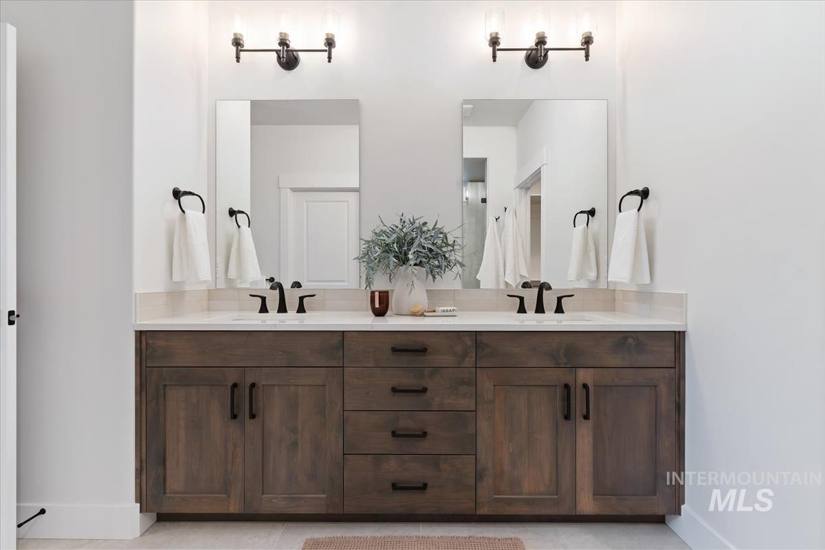 Full bathroom featuring double vanity and baseboards