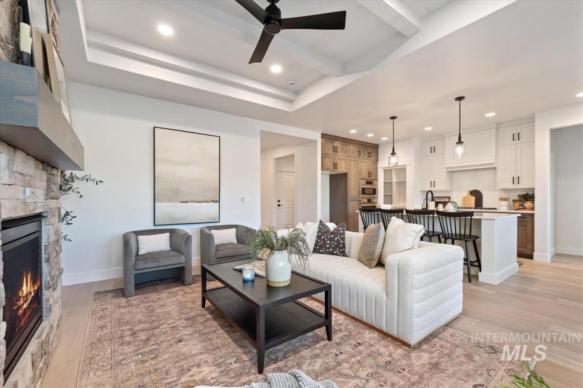 Living room with recessed lighting, light wood-type flooring, a stone fireplace, and a ceiling fan