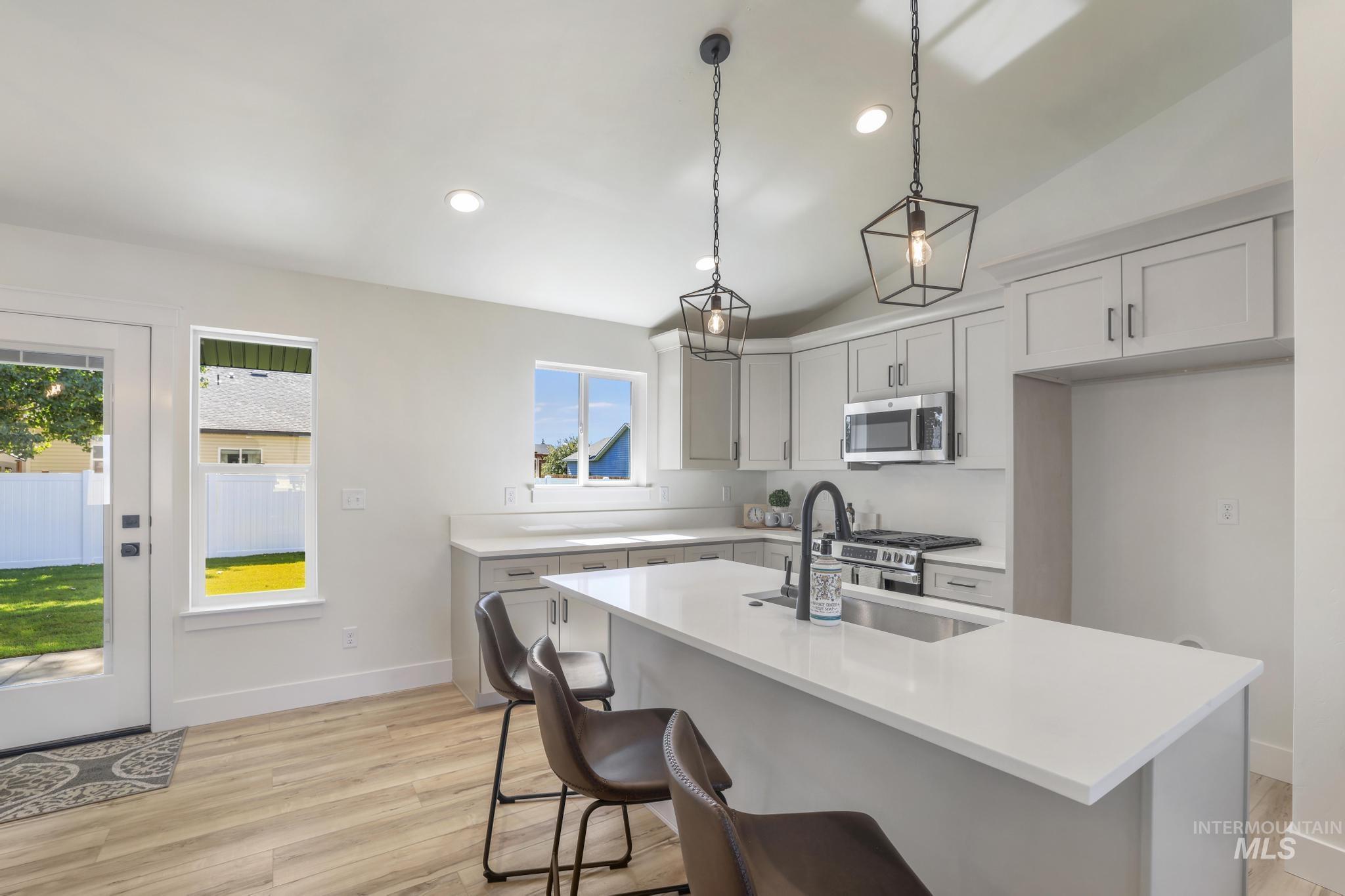 Kitchen featuring lofted ceiling, light wood-type flooring, a kitchen island with sink, appliances with stainless steel finishes, and recessed lighting